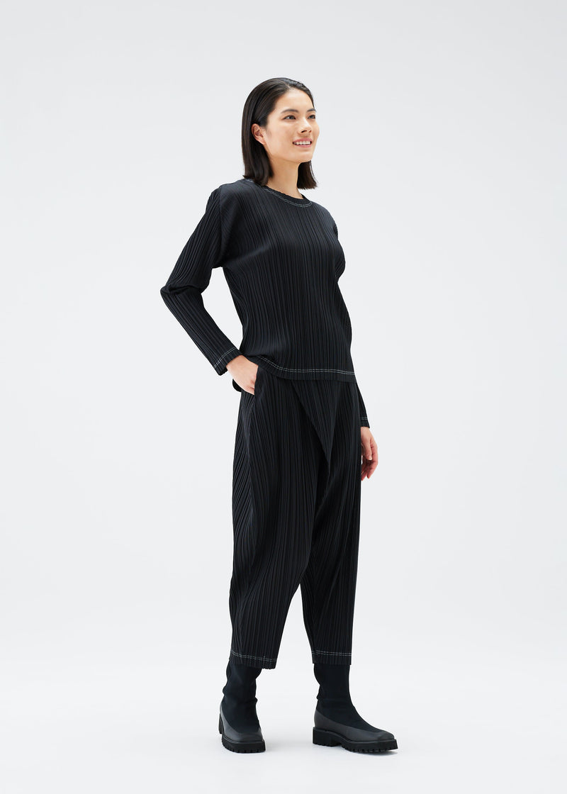 A model wears the PLEATS PLEASE ISSEY MIYAKE RAMIE PLEATS trousers.