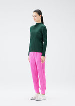 A model wears the PLEATS PLEASE ISSEY MIYAKE CREPE KNIT trousers.