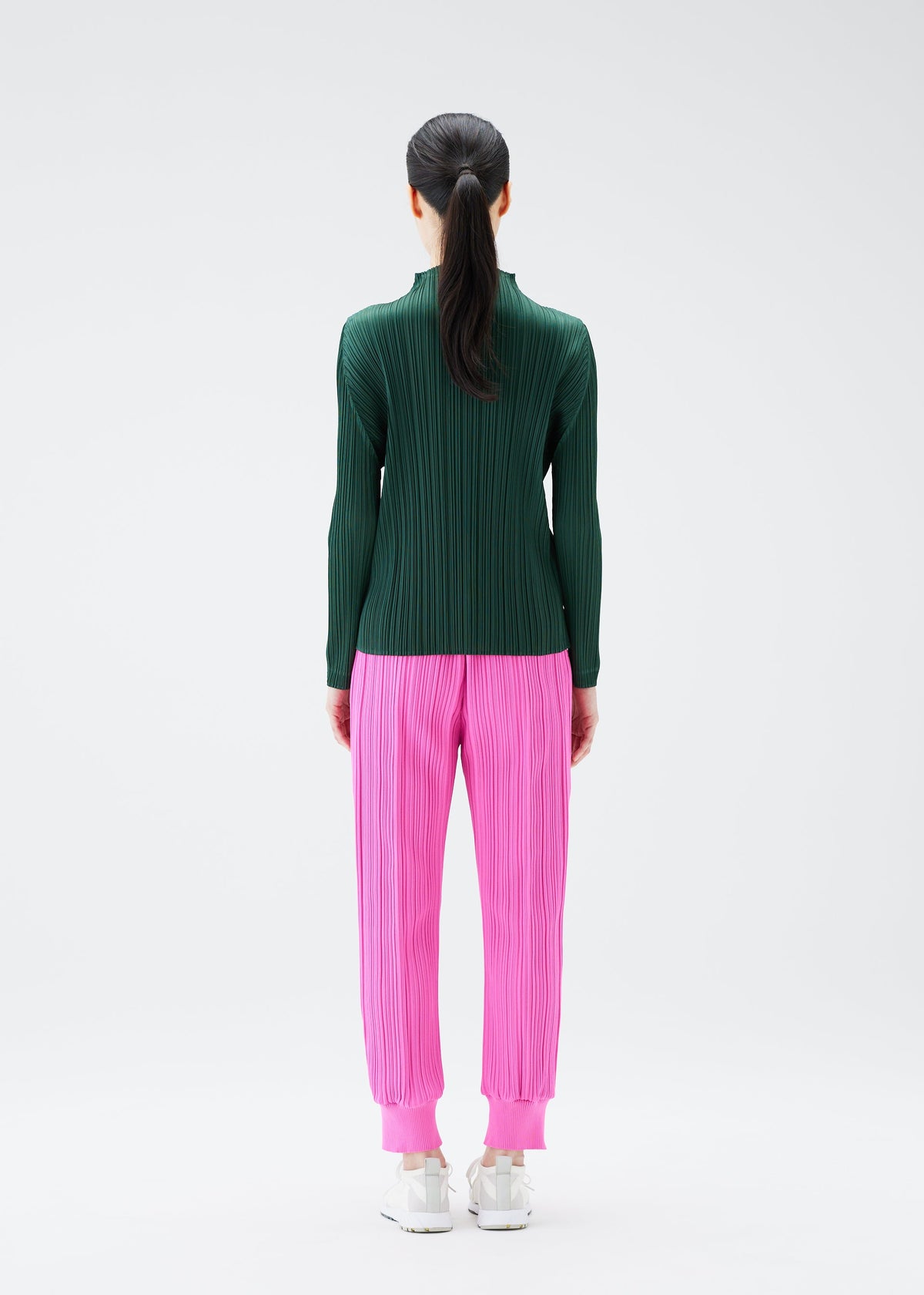 A model wears the PLEATS PLEASE ISSEY MIYAKE CREPE KNIT trousers.