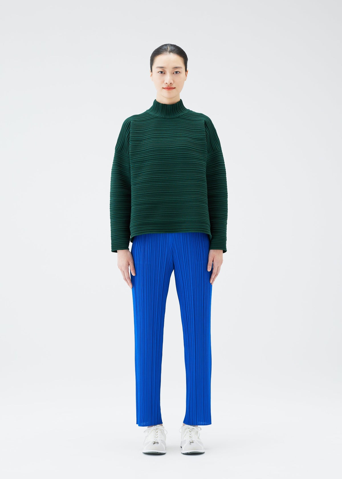 A model wears the PLEATS PLEASE ISSEY MIYAKE CREPE KNIT top.