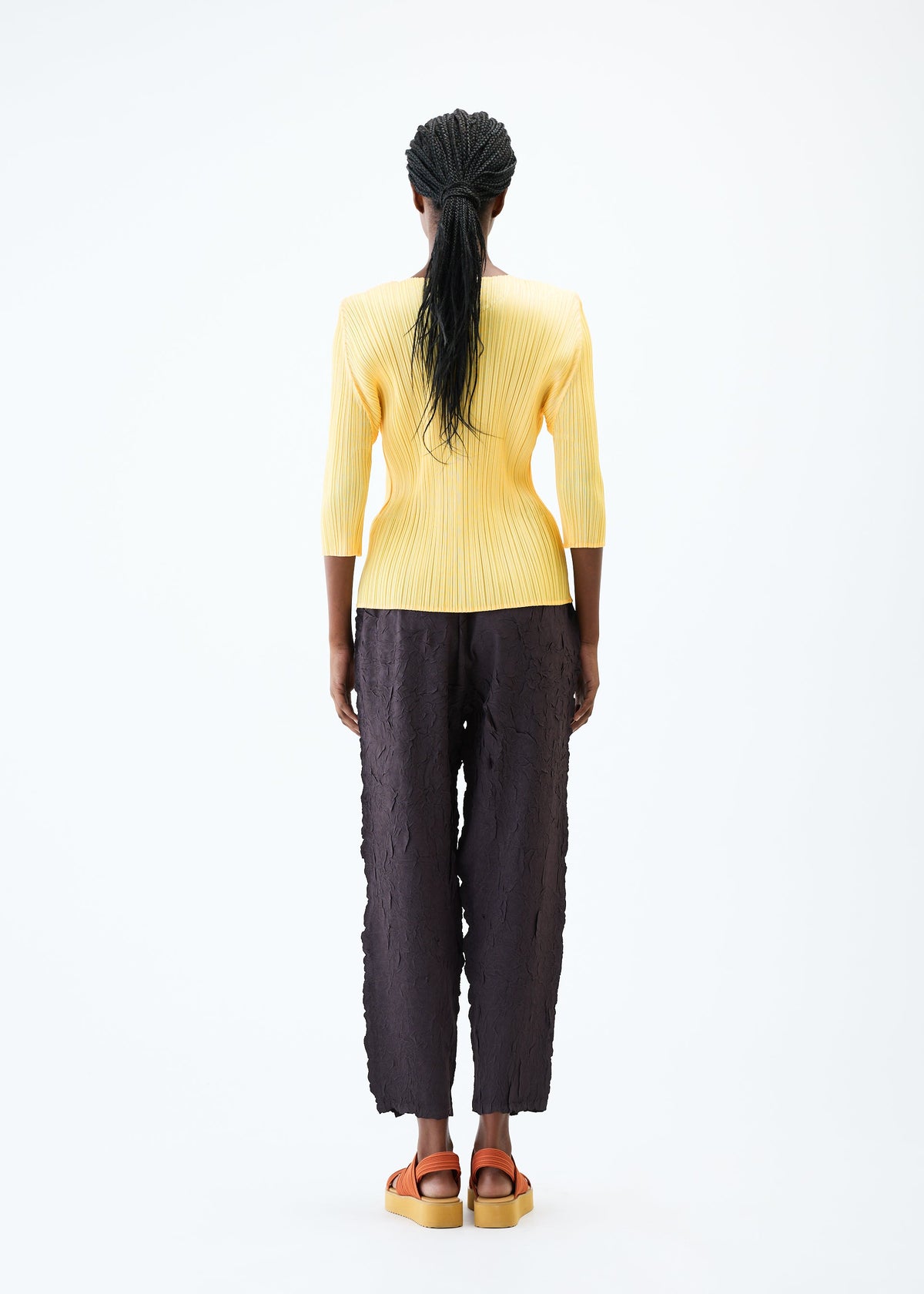 A model wears the PLEATS PLEASE ISSEY MIYAKE CRUSH PRESS trousers.