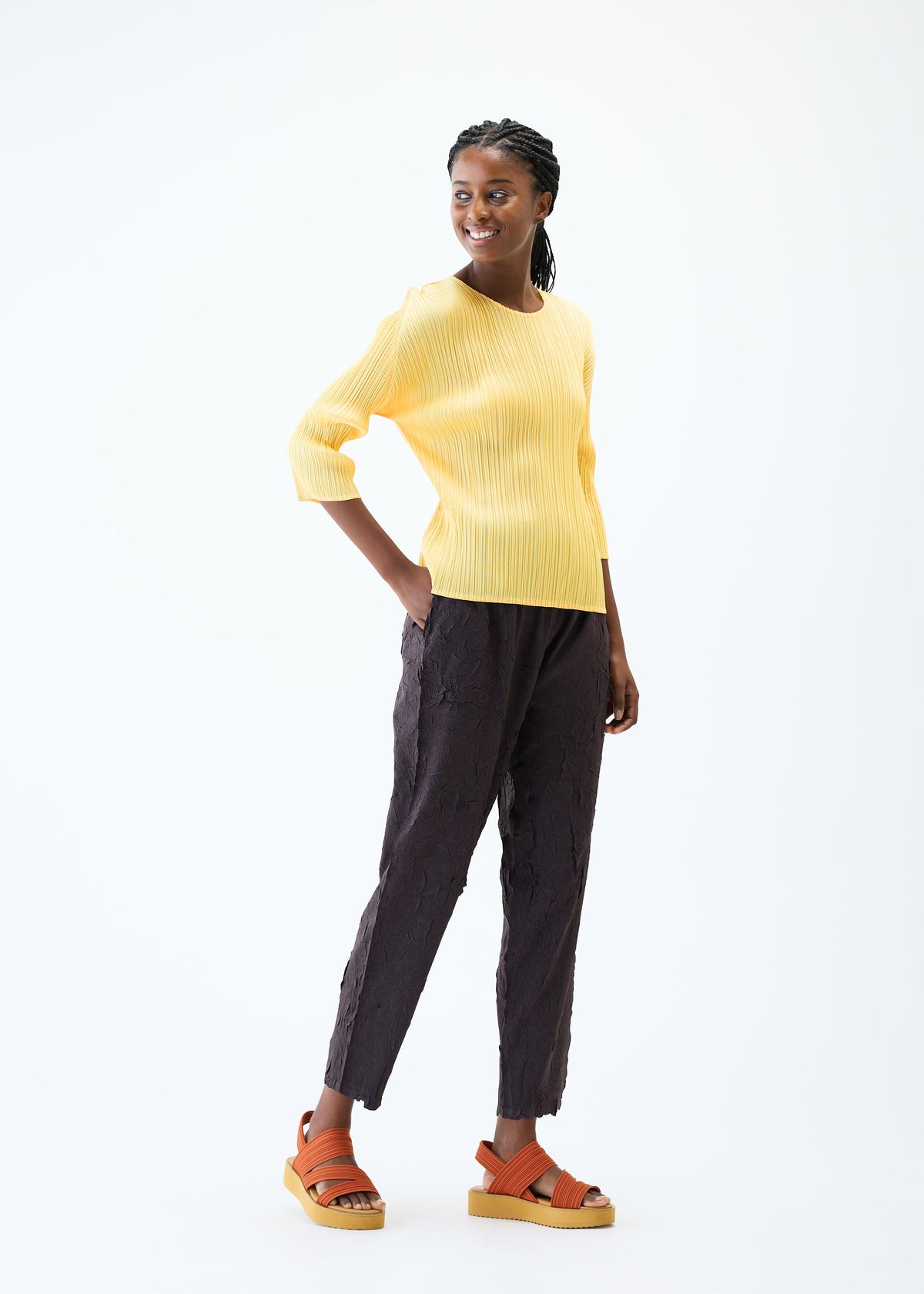 A model wears the PLEATS PLEASE ISSEY MIYAKE CRUSH PRESS trousers.