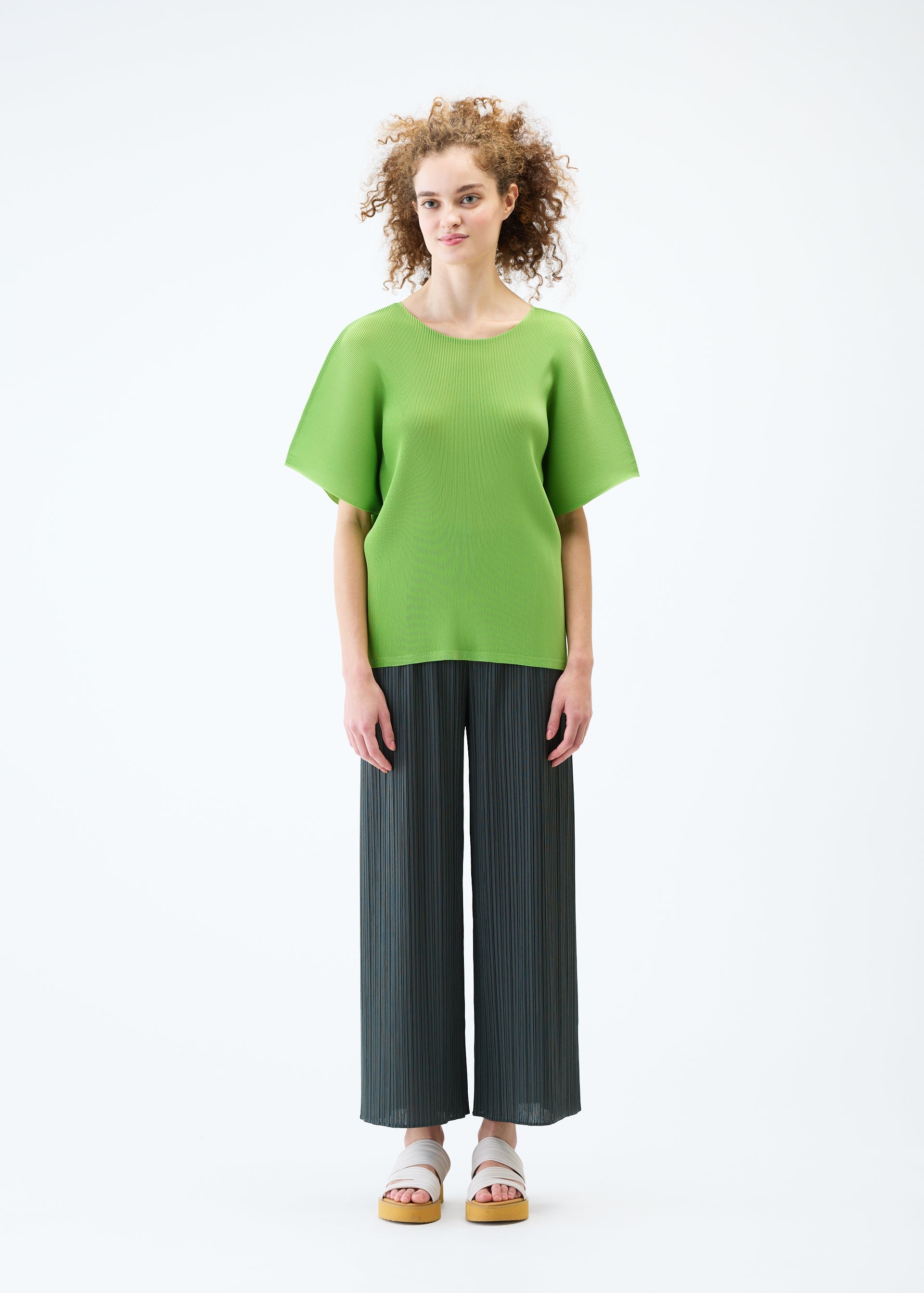 A model wears the PLEATS PLEASE ISSEY MIYAKE MIST JUNE top.