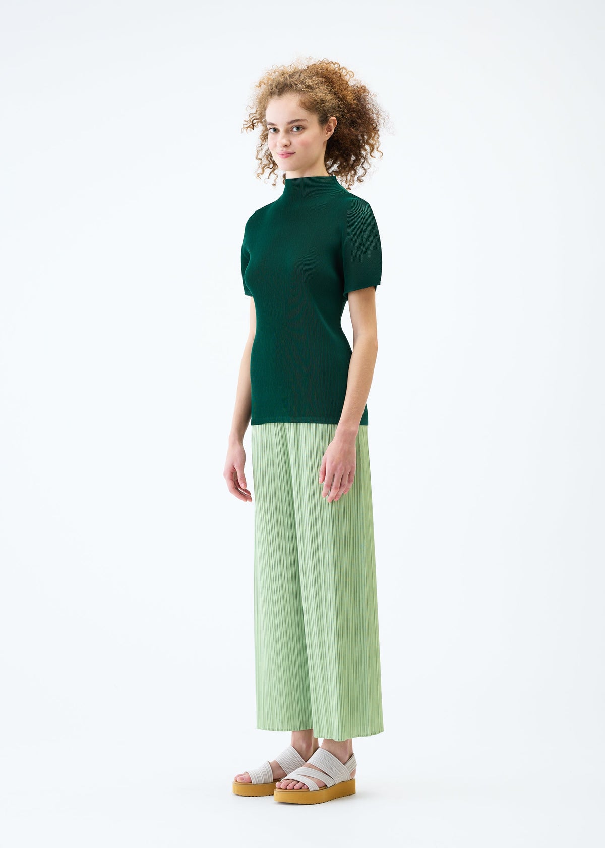 A model wears the PLEATS PLEASE ISSEY MIYAKE MIST JUNE top.