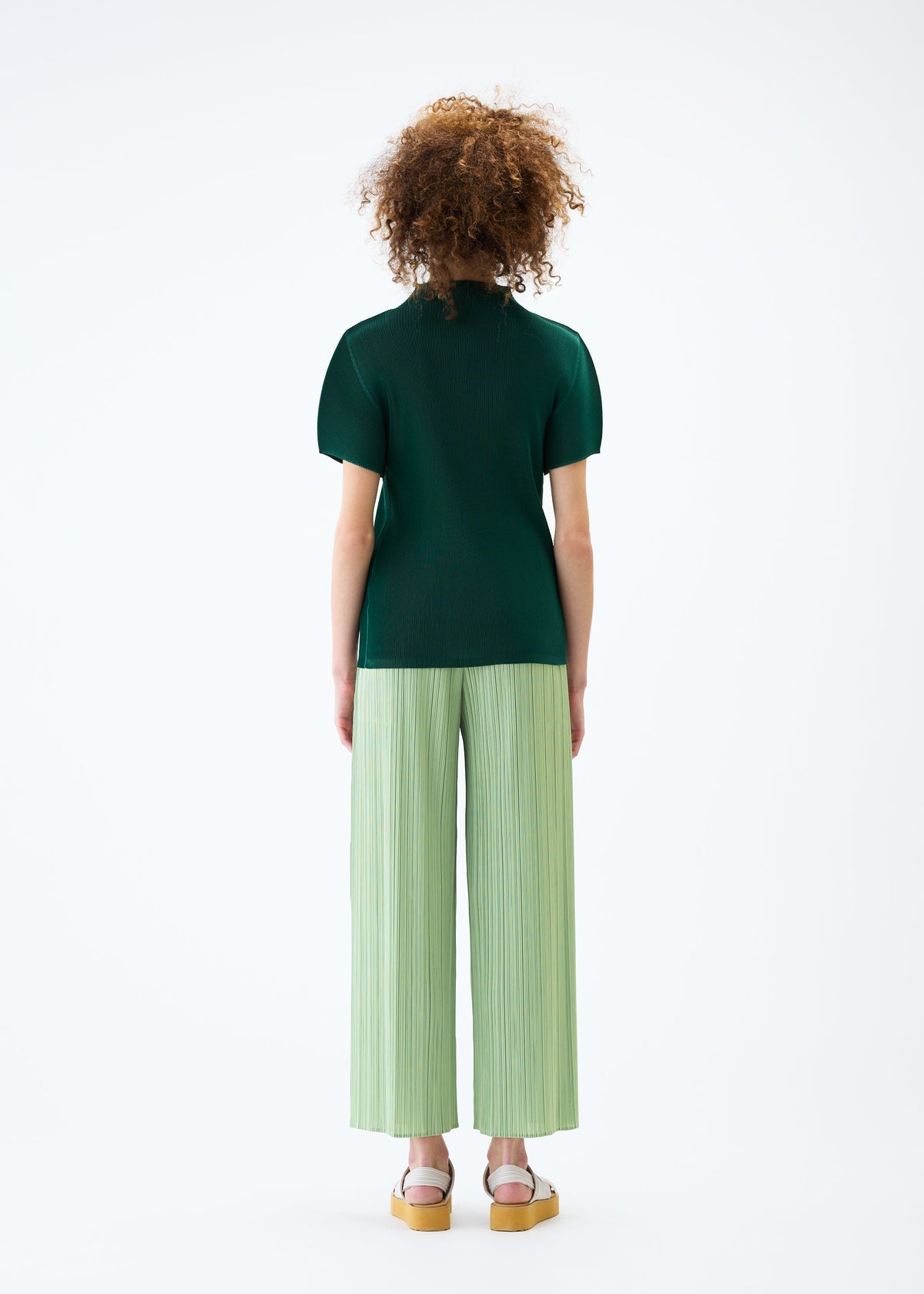 A model wears the PLEATS PLEASE ISSEY MIYAKE MIST JUNE top.