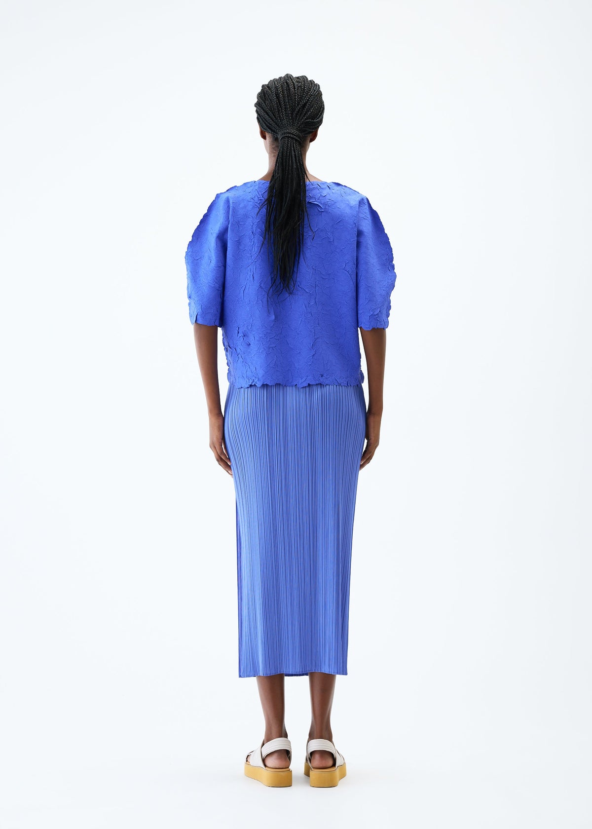 A model wears the PLEATS PLEASE ISSEY MIYAKE CRUSH PRESS top.