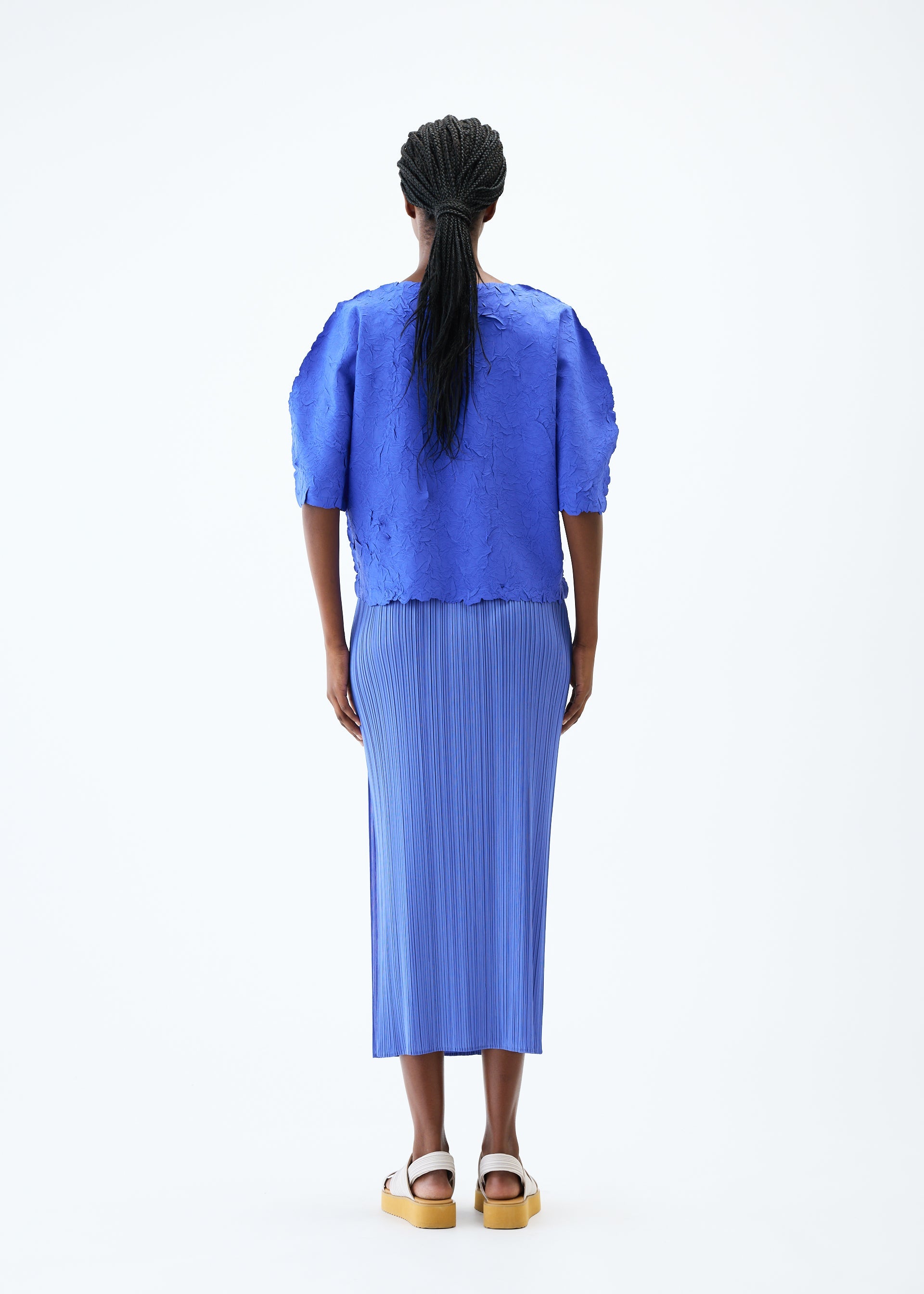 A model wears the PLEATS PLEASE ISSEY MIYAKE CRUSH PRESS top.