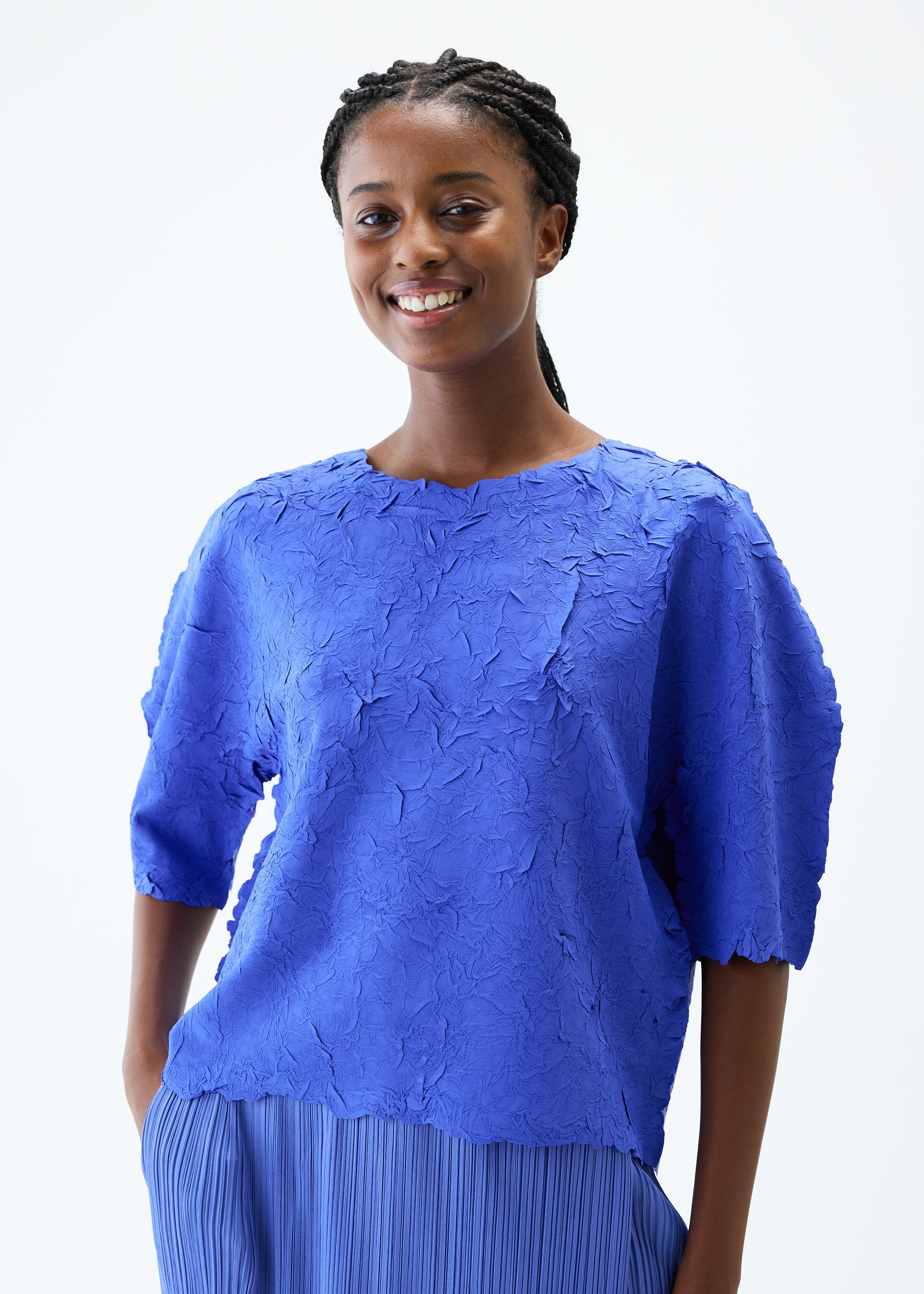 A model wears the PLEATS PLEASE ISSEY MIYAKE CRUSH PRESS top.