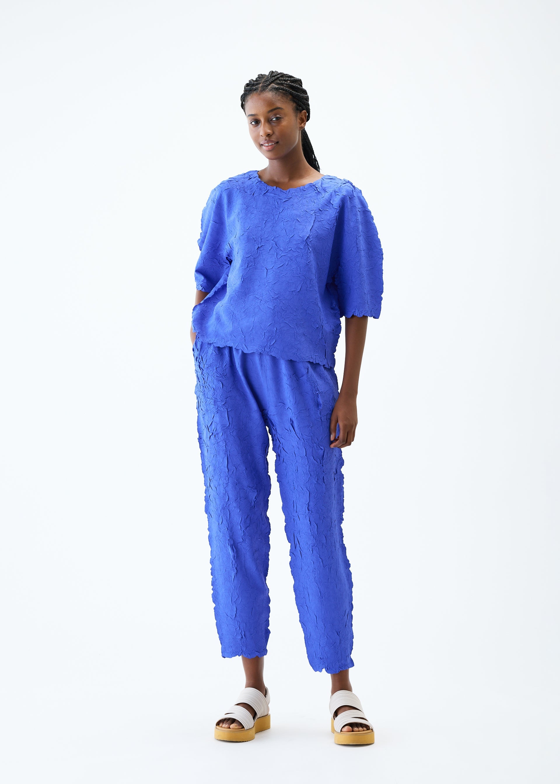 A model wears the PLEATS PLEASE ISSEY MIYAKE CRUSH PRESS top.