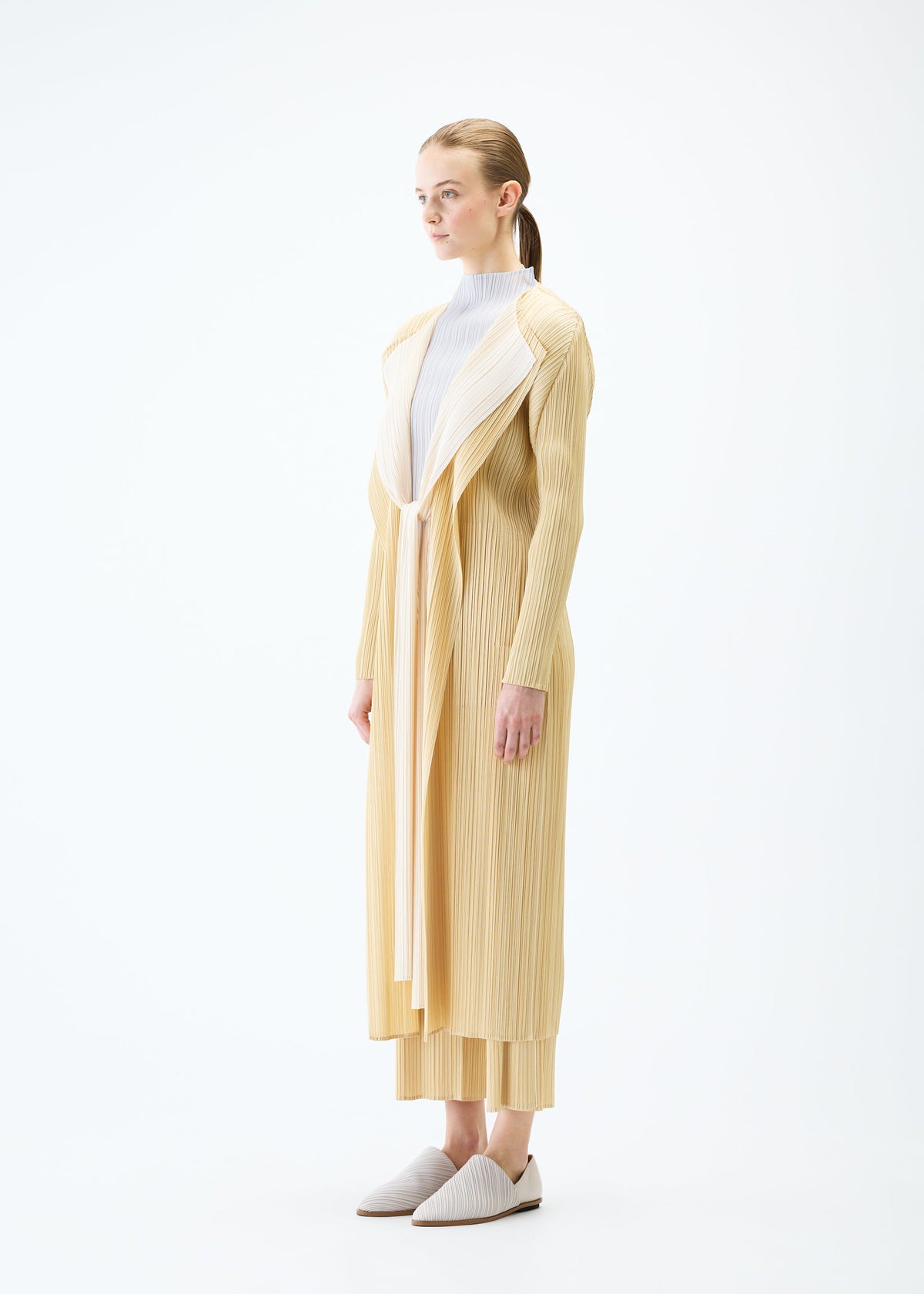 A model wears the PLEATS PLEASE ISSEY MIYAKE MERRY BICOLOR coat.
