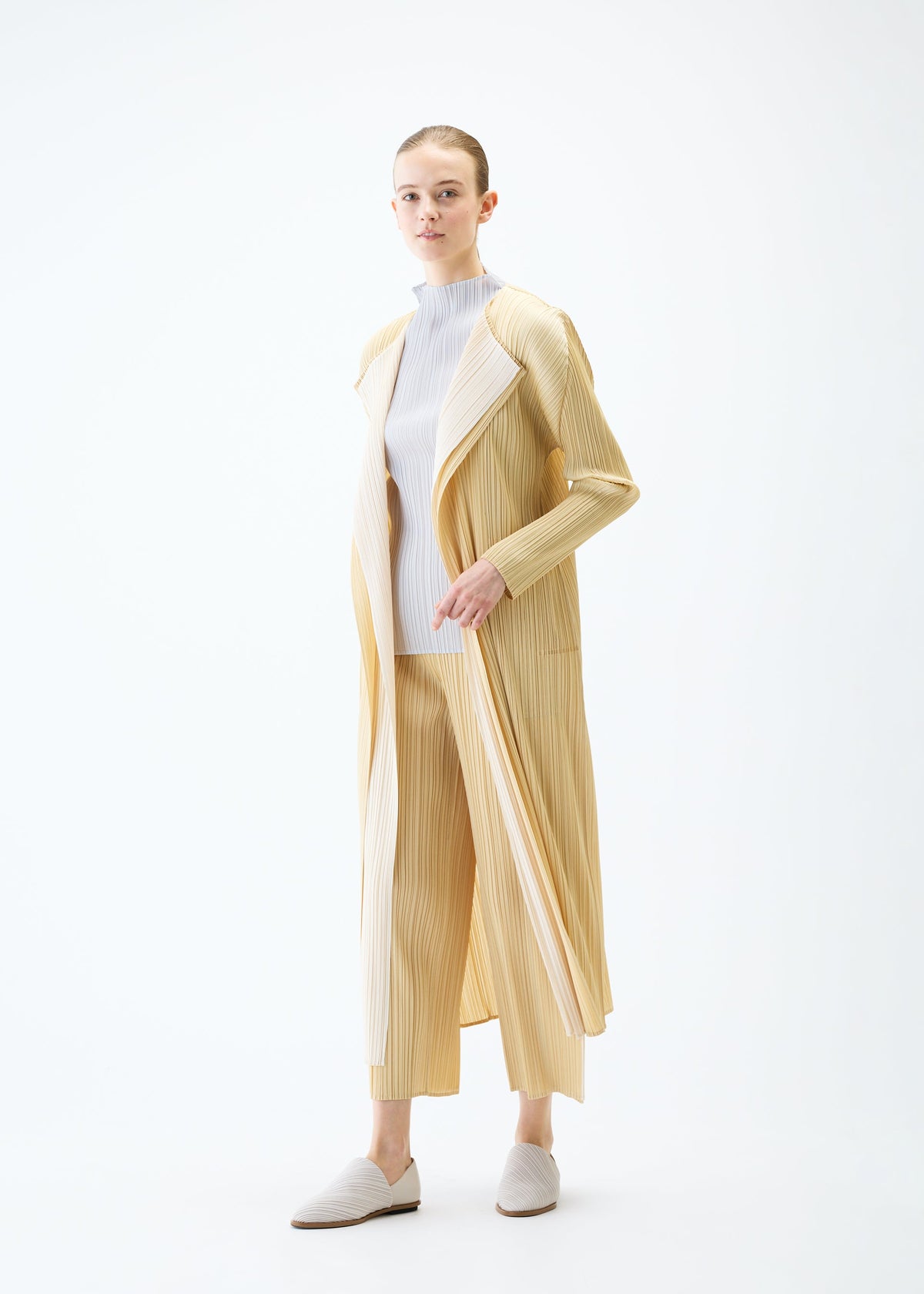 A model wears the PLEATS PLEASE ISSEY MIYAKE MERRY BICOLOR coat.