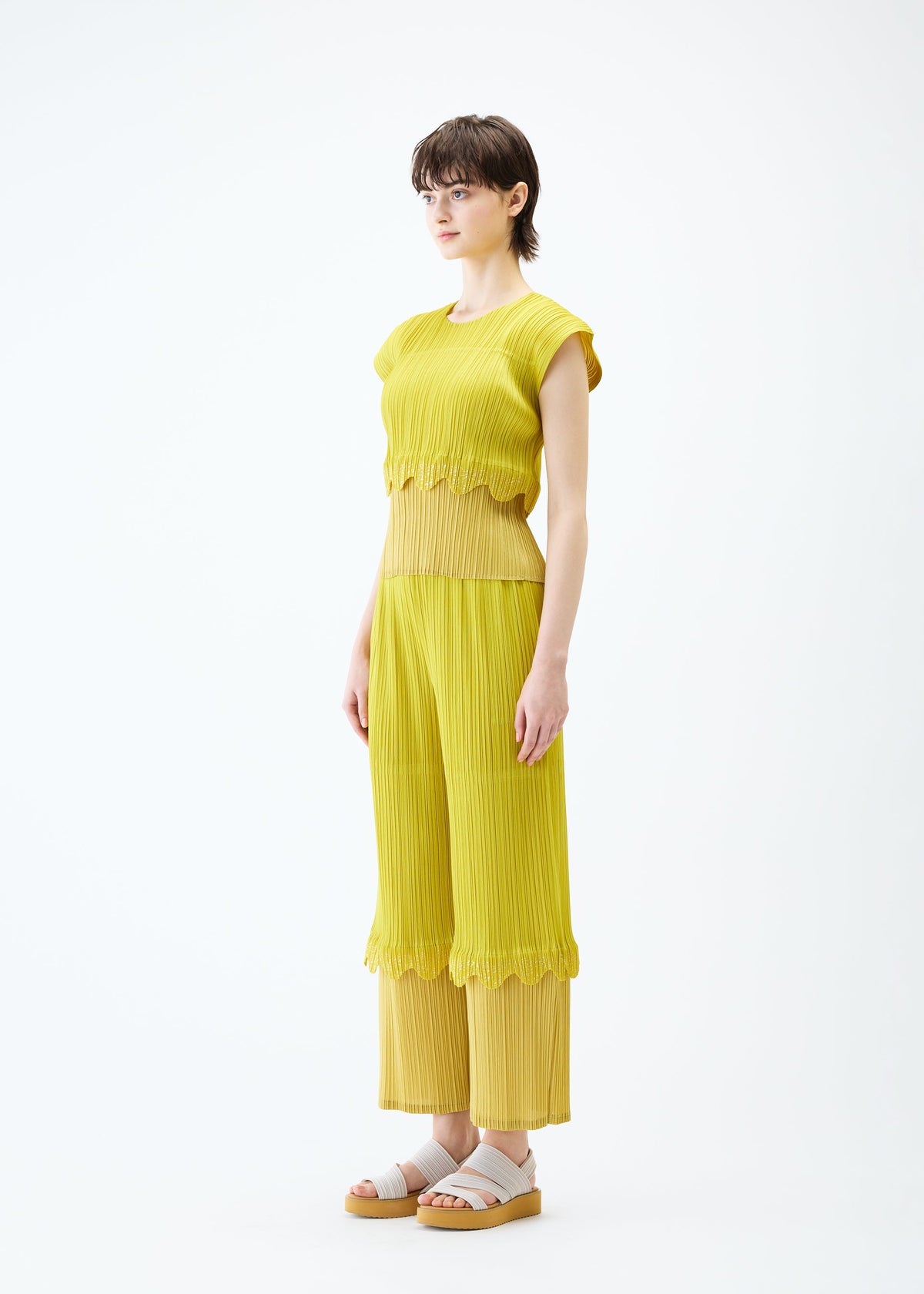 A model wears the PLEATS PLEASE ISSEY MIYAKE TWINKLE trousers.