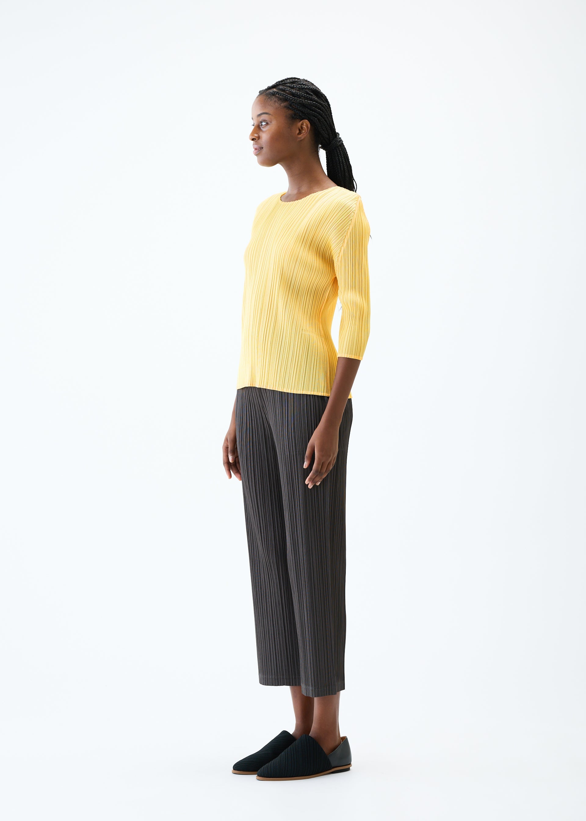 A model wears the PLEATS PLEASE ISSEY MIYAKE THICKER BOTTOMS 2 trousers.