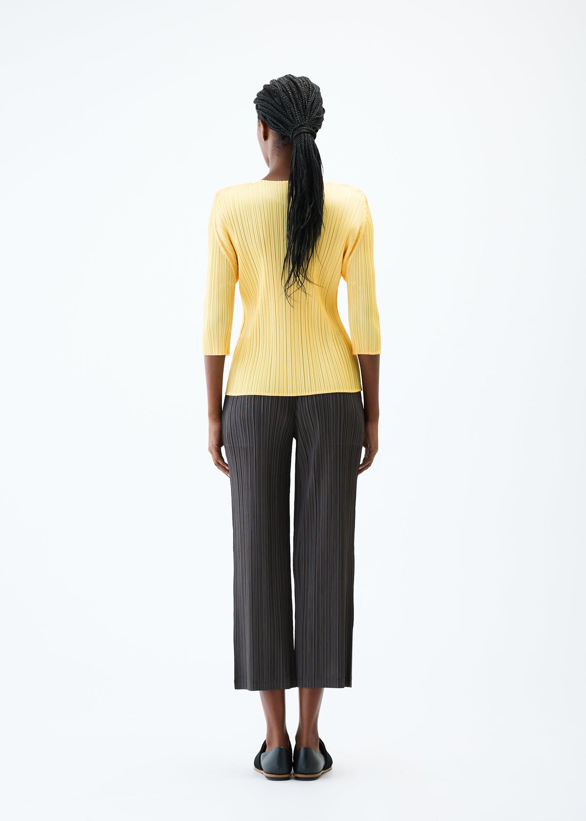 A model wears the PLEATS PLEASE ISSEY MIYAKE THICKER BOTTOMS 2 trousers.