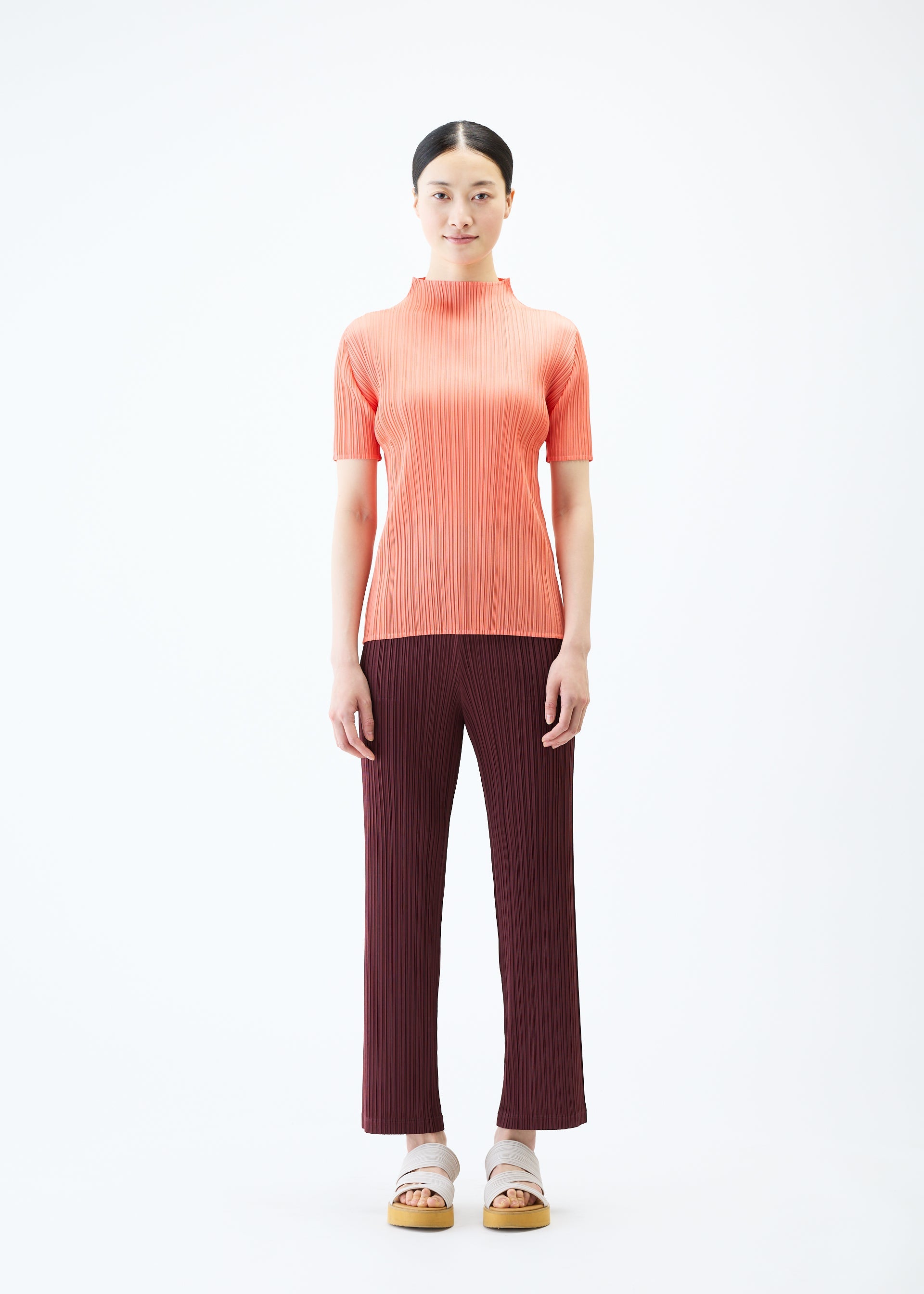 A model wears the PLEATS PLEASE ISSEY MIYAKE LOOP BOTTOMS trousers.