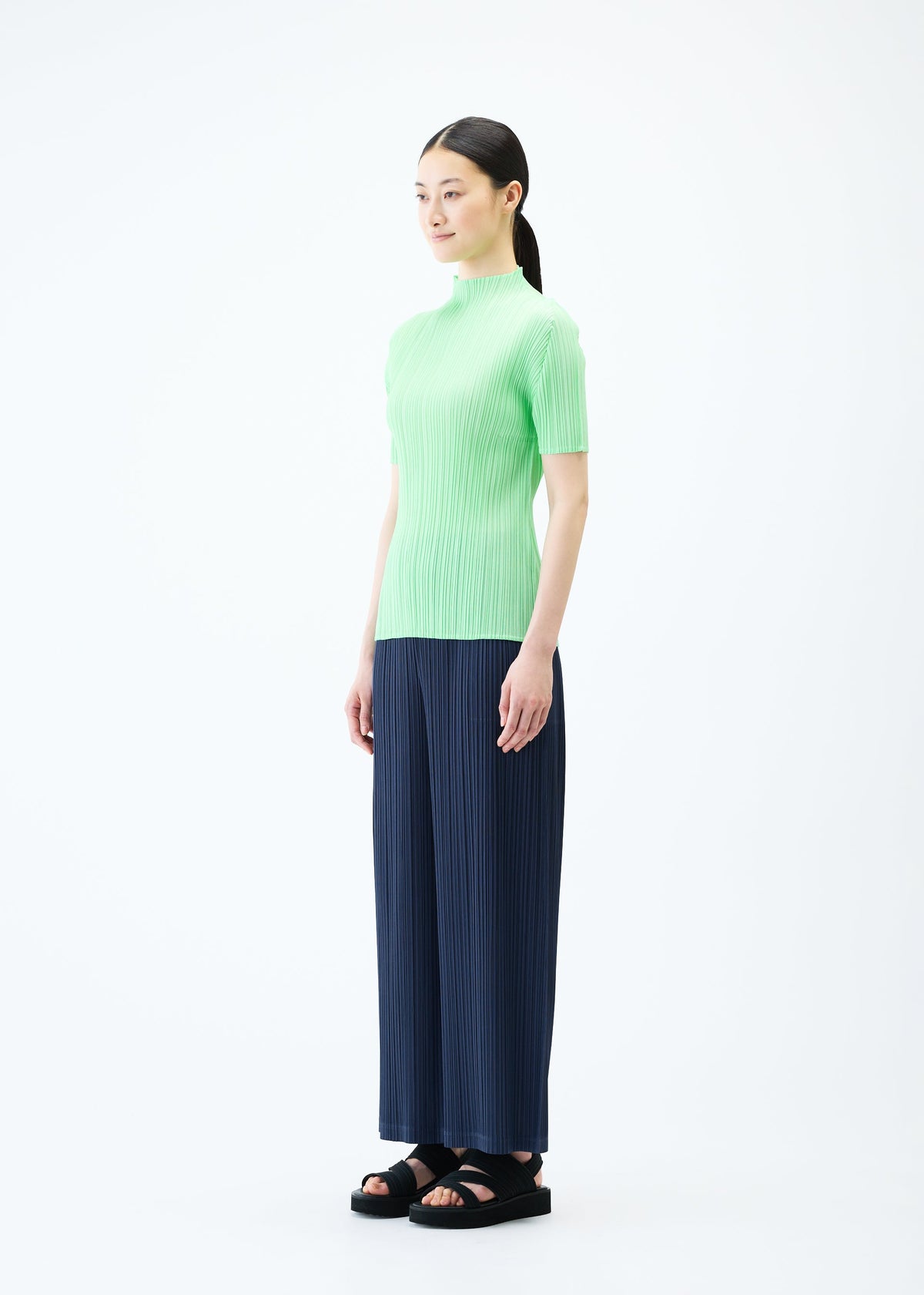 A model wears the PLEATS PLEASE ISSEY MIYAKE LOOP BOTTOMS trousers.