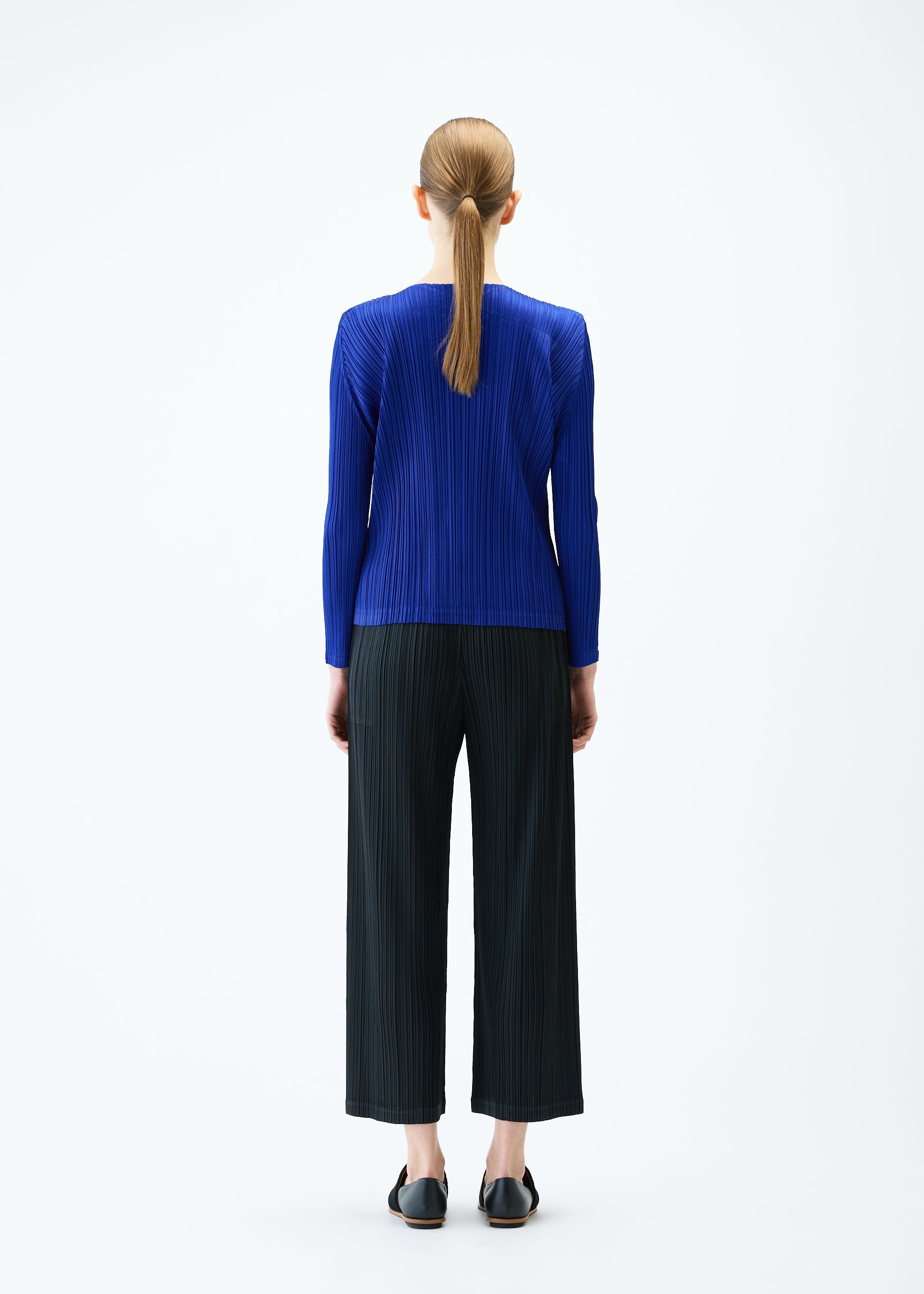 A model wears the PLEATS PLEASE ISSEY MIYAKE LIGHT WAVE trousers.