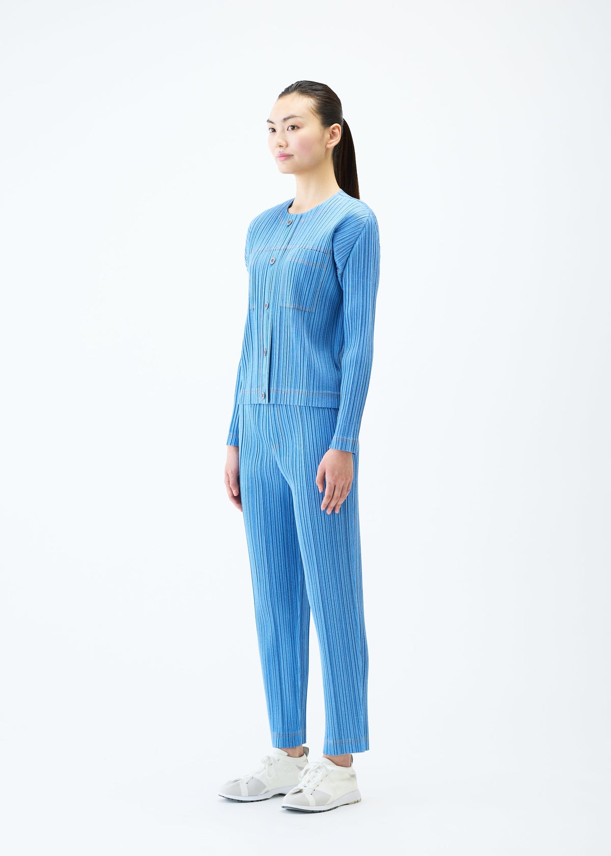 A model wears the PLEATS PLEASE ISSEY MIYAKE COTTON DENIM trousers.