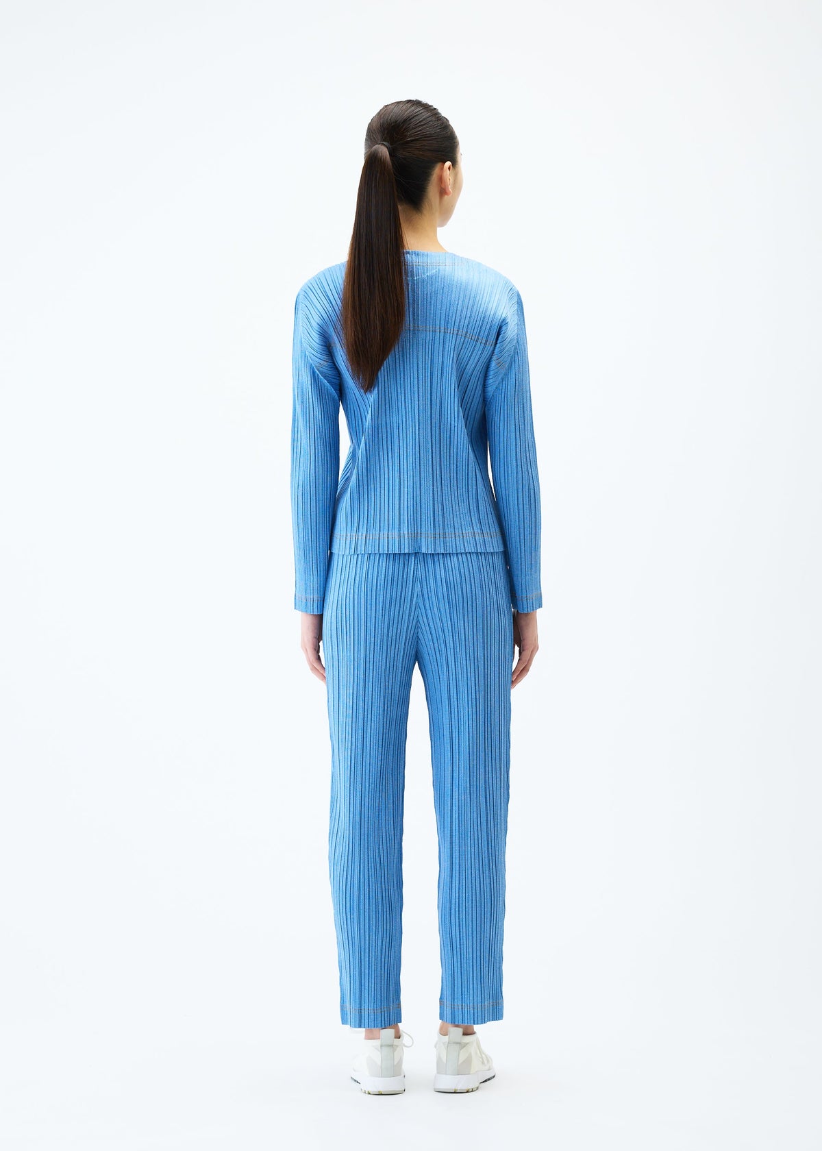 A model wears the PLEATS PLEASE ISSEY MIYAKE COTTON DENIM trousers.