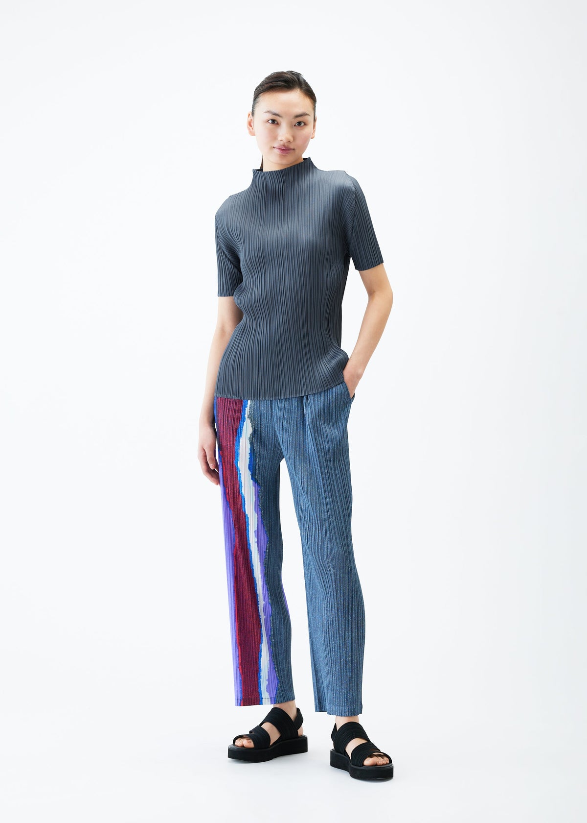 A model wears the PLEATS PLEASE ISSEY MIYAKE GRAINY COLORS trousers.