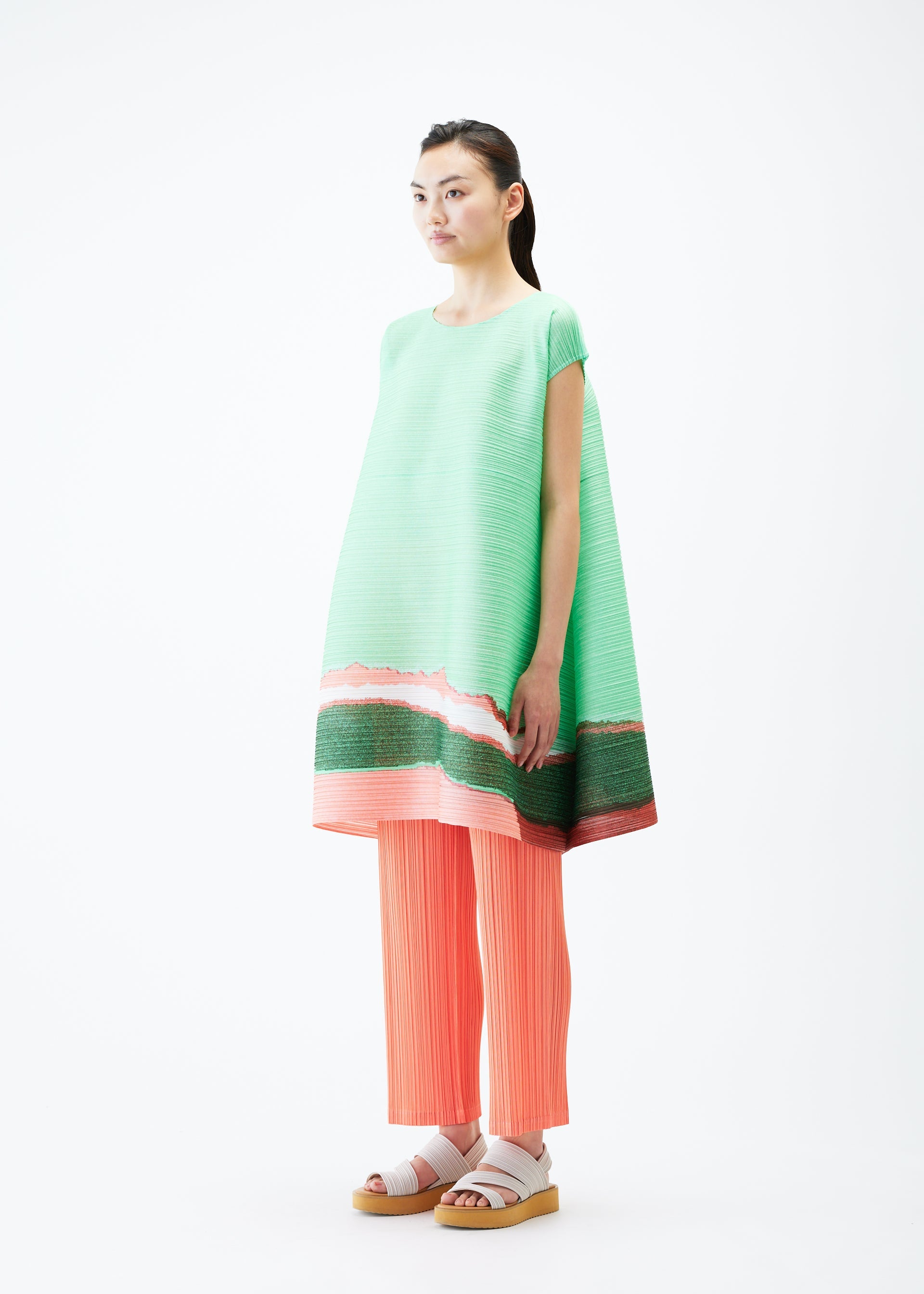A model wears the PLEATS PLEASE ISSEY MIYAKE GRAINY COLORS tunic.