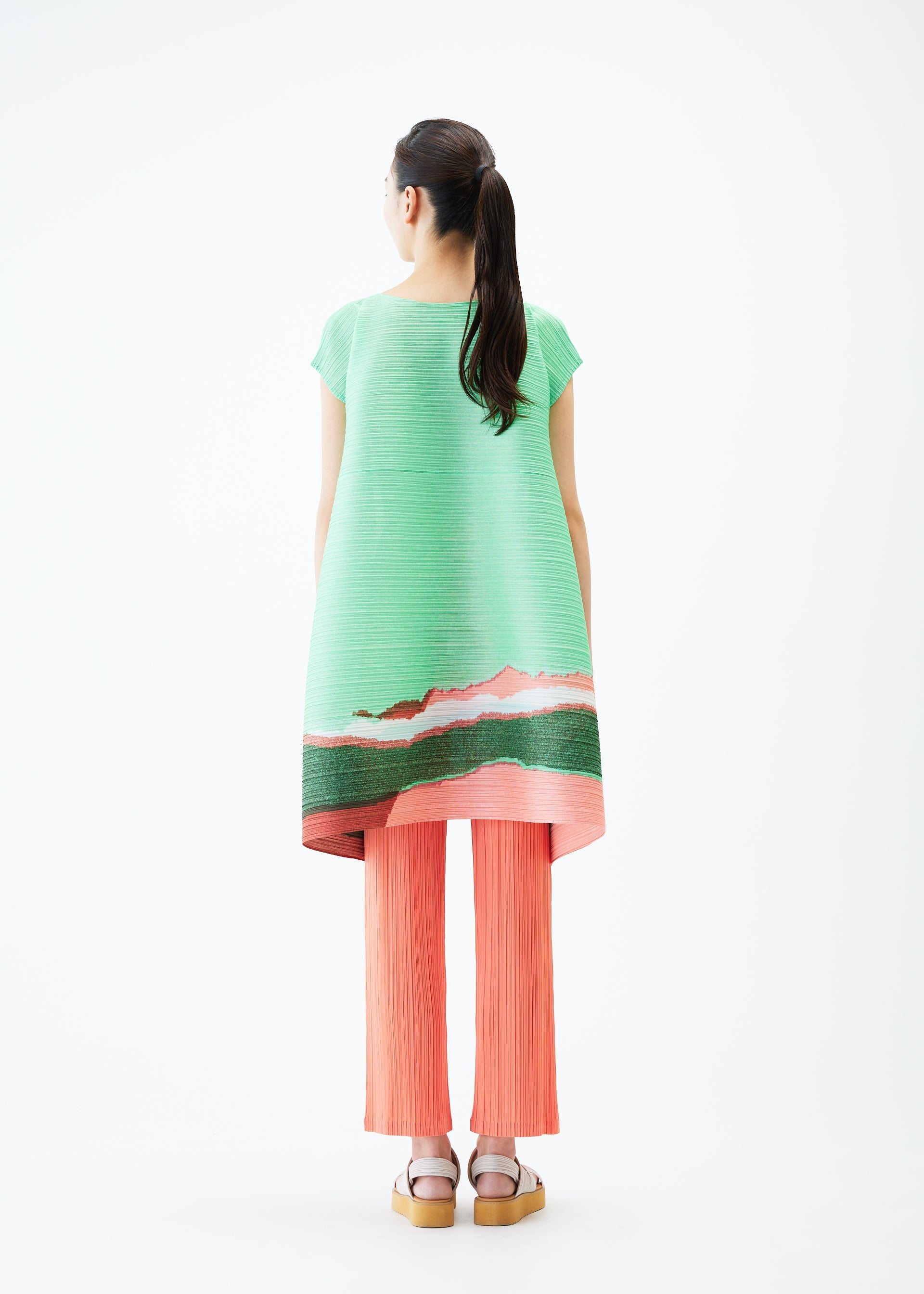 A model wears the PLEATS PLEASE ISSEY MIYAKE GRAINY COLORS tunic.