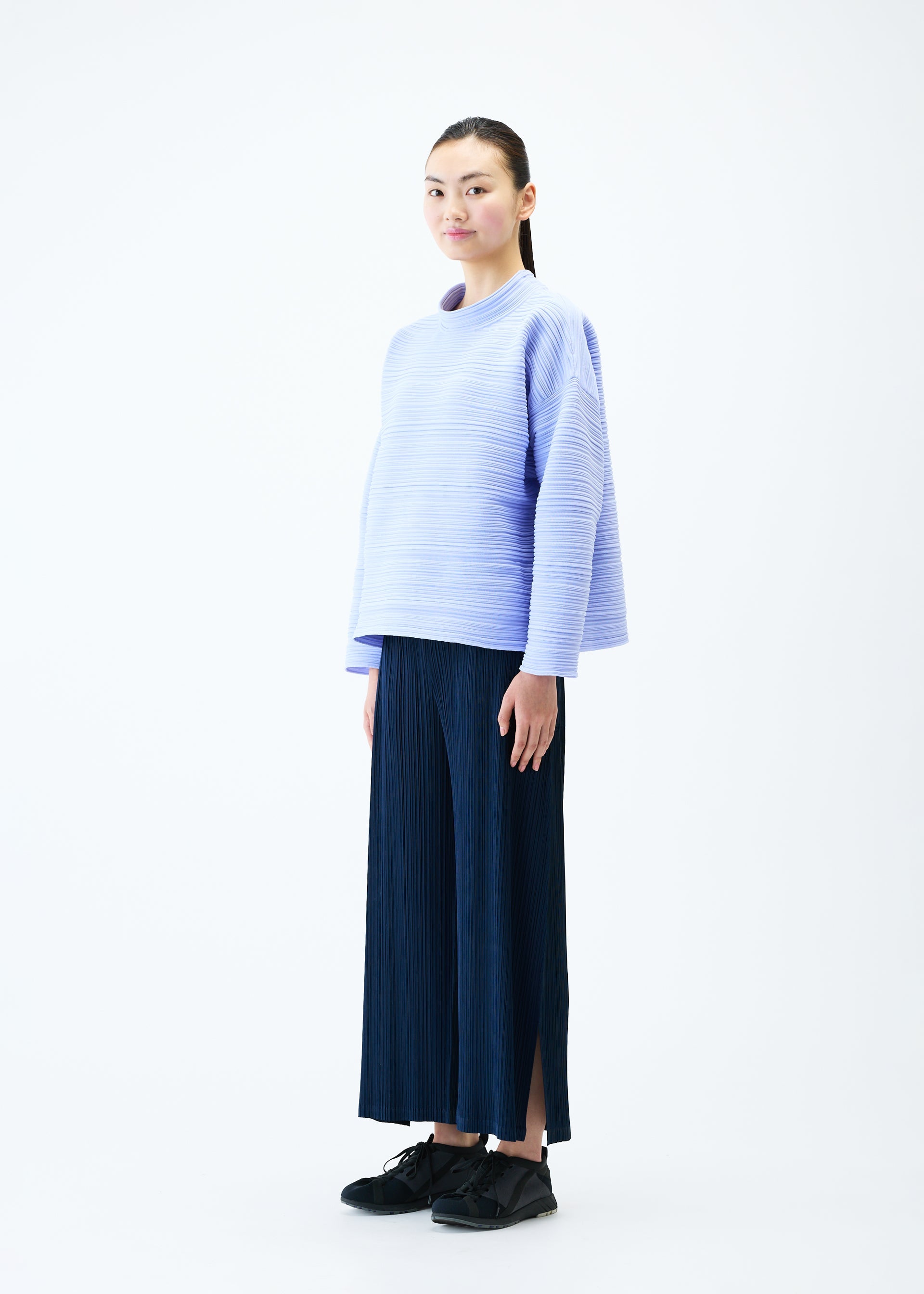 A model wears the PLEATS PLEASE ISSEY MIYAKE CREPE KNIT top.