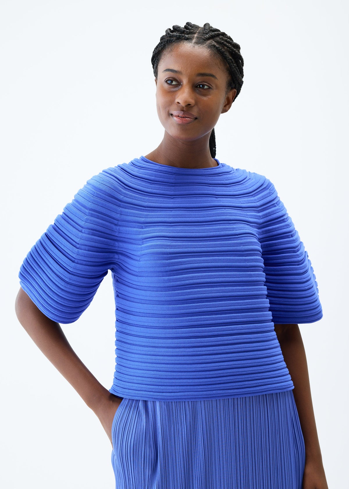 A model wears the PLEATS PLEASE ISSEY MIYAKE MUSHROOM KNIT top.