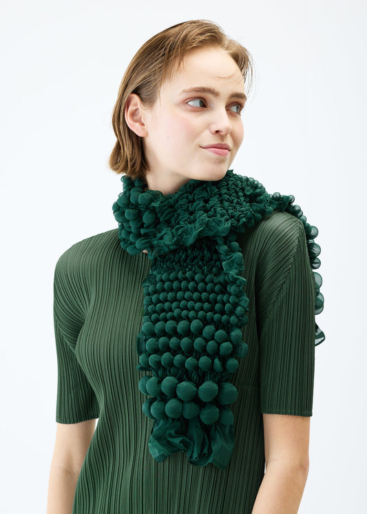 A model wears the PLEATS PLEASE ISSEY MIYAKE GRAINY DOTS SHIBORI SCARF stole.