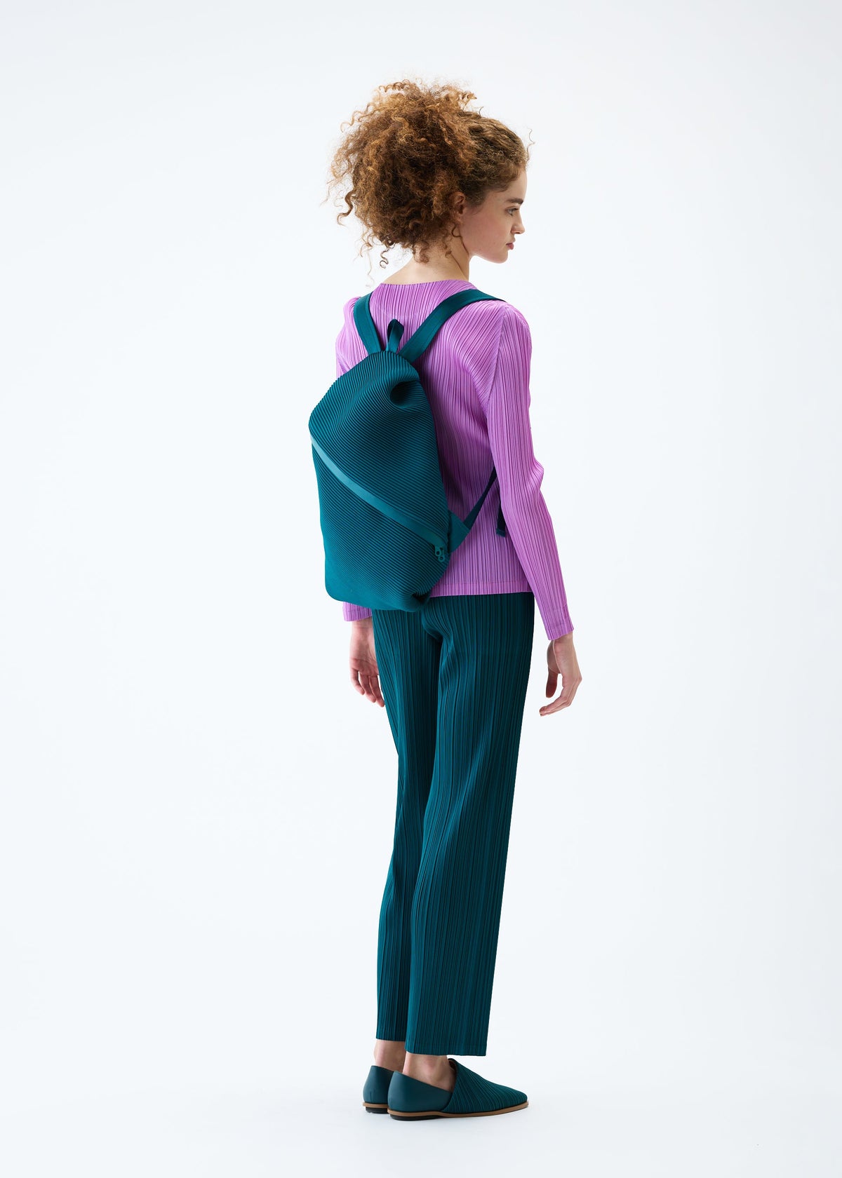 A model wears the PLEATS PLEASE ISSEY MIYAKE BIAS PLEATS BACKPACK bag.