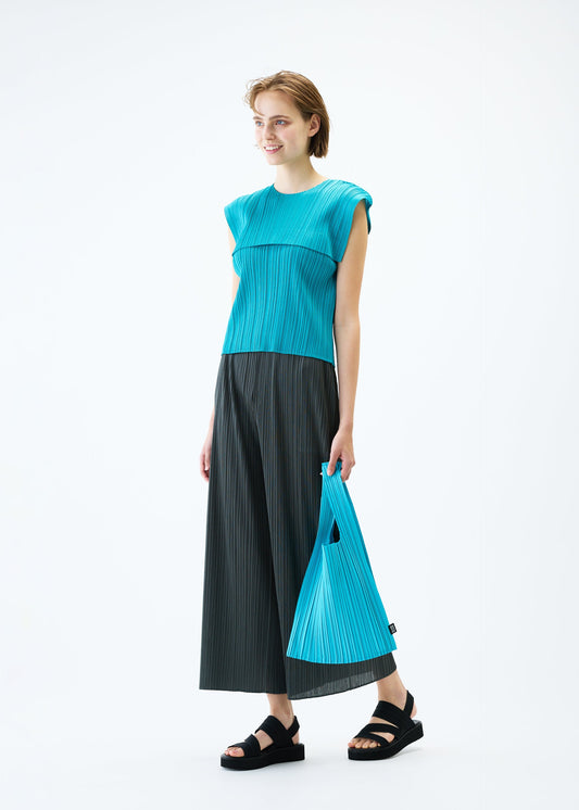A model wears the PLEATS PLEASE ISSEY MIYAKE PLEATS SHOPPING TOTE bag.