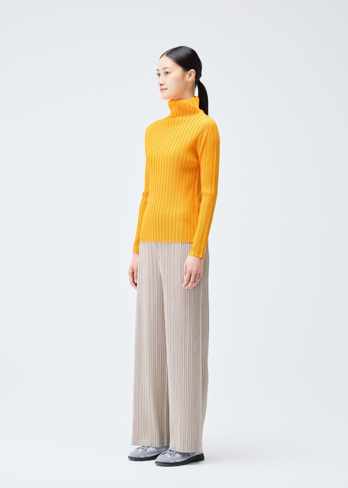 A model wears the PLEATS PLEASE ISSEY MIYAKE RIB PLEATS DECEMBER clothing.