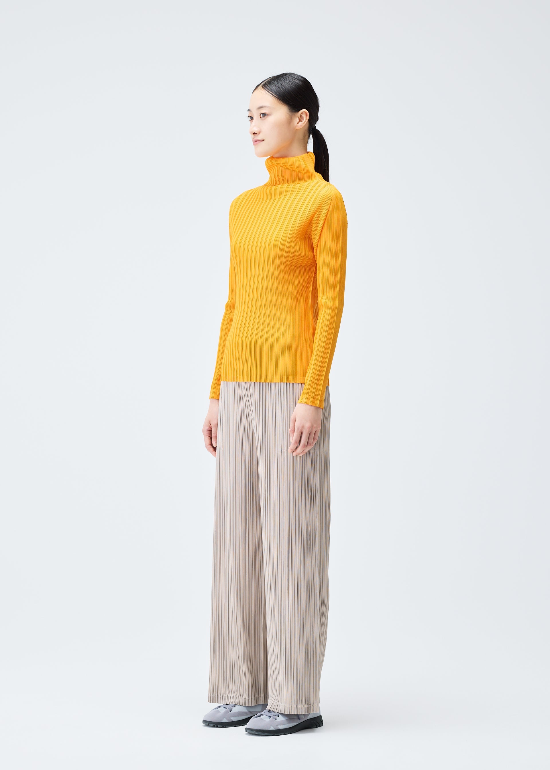 A model wears the PLEATS PLEASE ISSEY MIYAKE RIB PLEATS DECEMBER clothing.