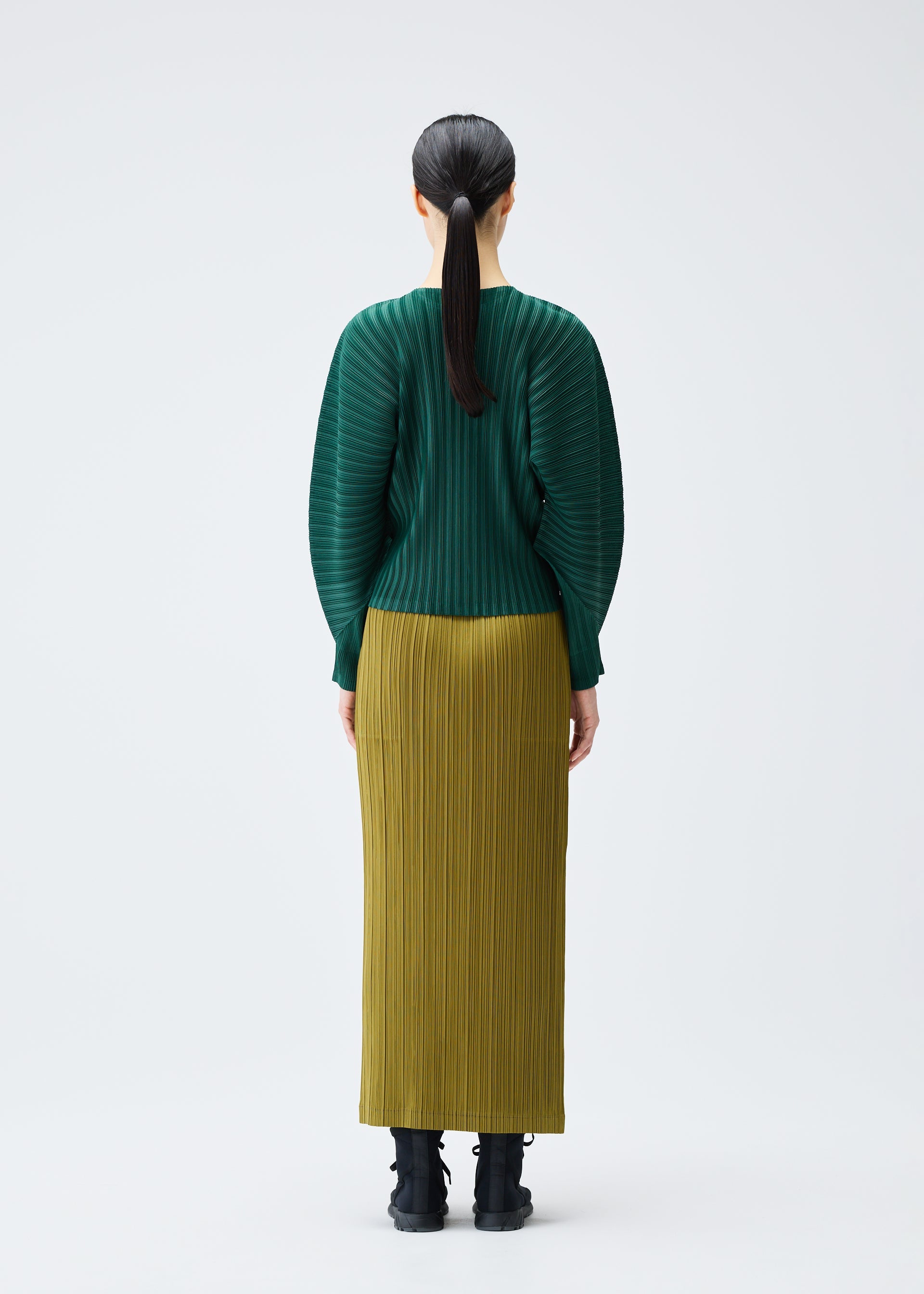 A model wears the PLEATS PLEASE ISSEY MIYAKE RIB PLEATS DECEMBER clothing.