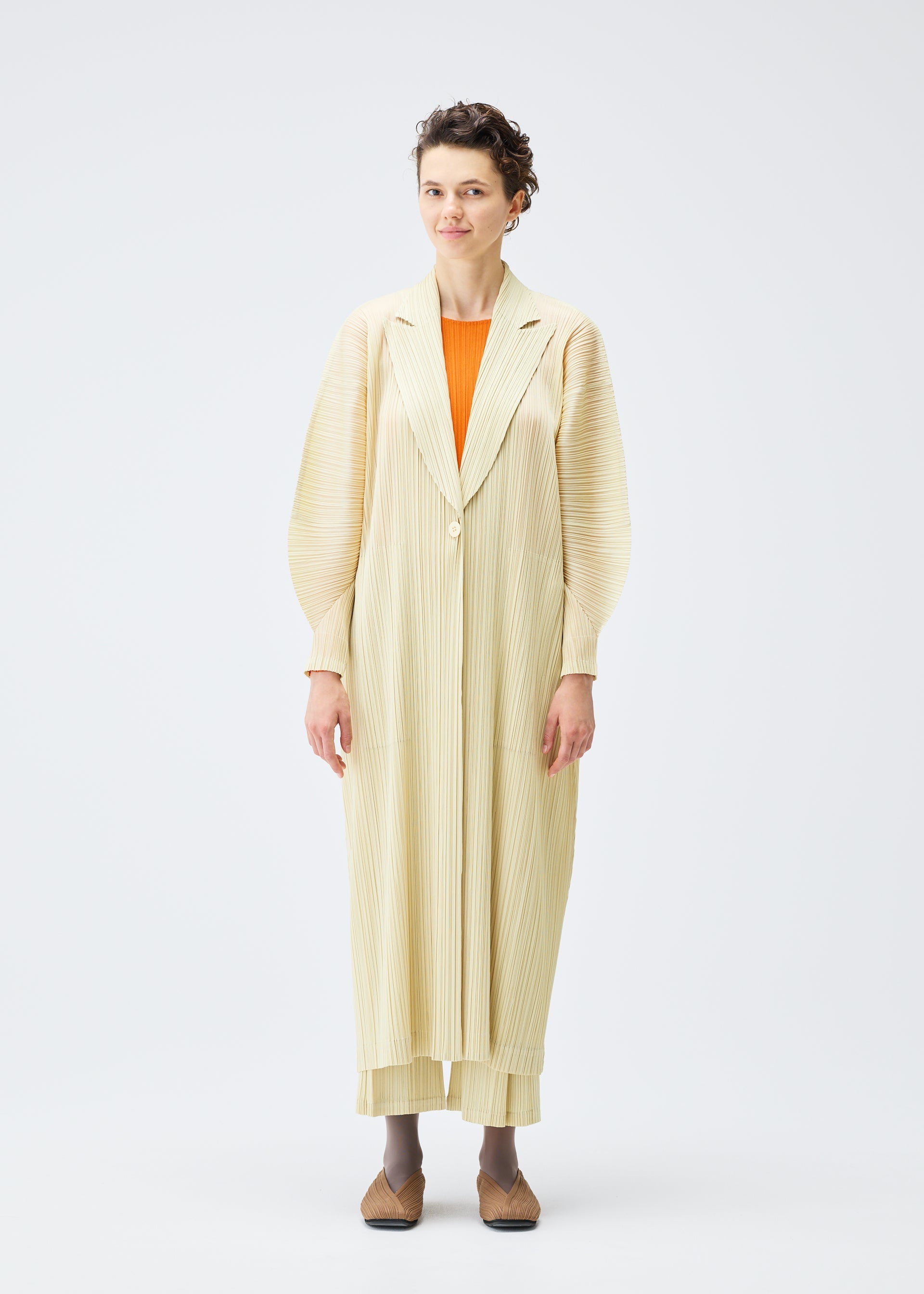 A model wears the PLEATS PLEASE ISSEY MIYAKE MONTHLY COLORS DECEMBER clothing.