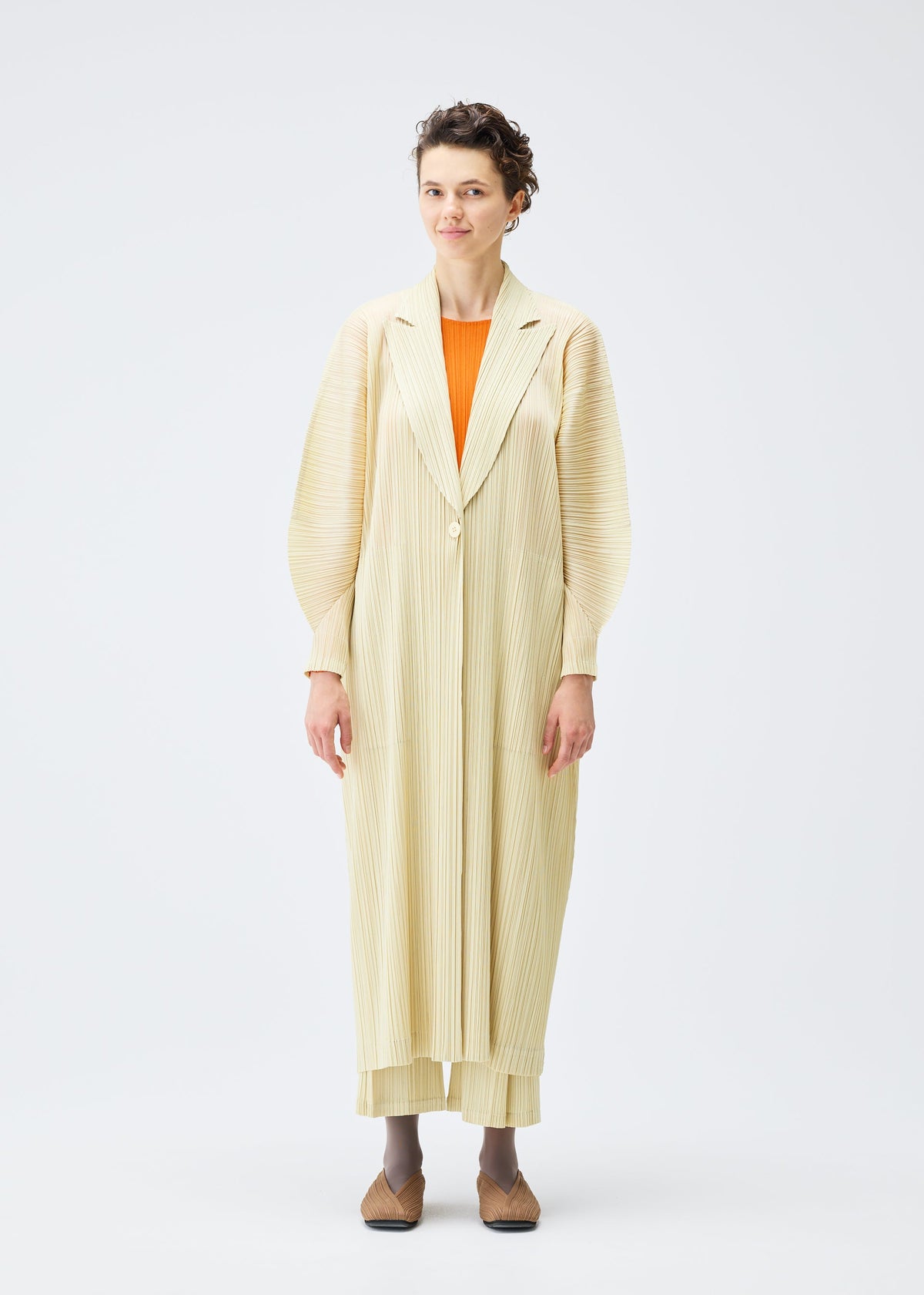 A model wears the PLEATS PLEASE ISSEY MIYAKE MONTHLY COLORS DECEMBER clothing.