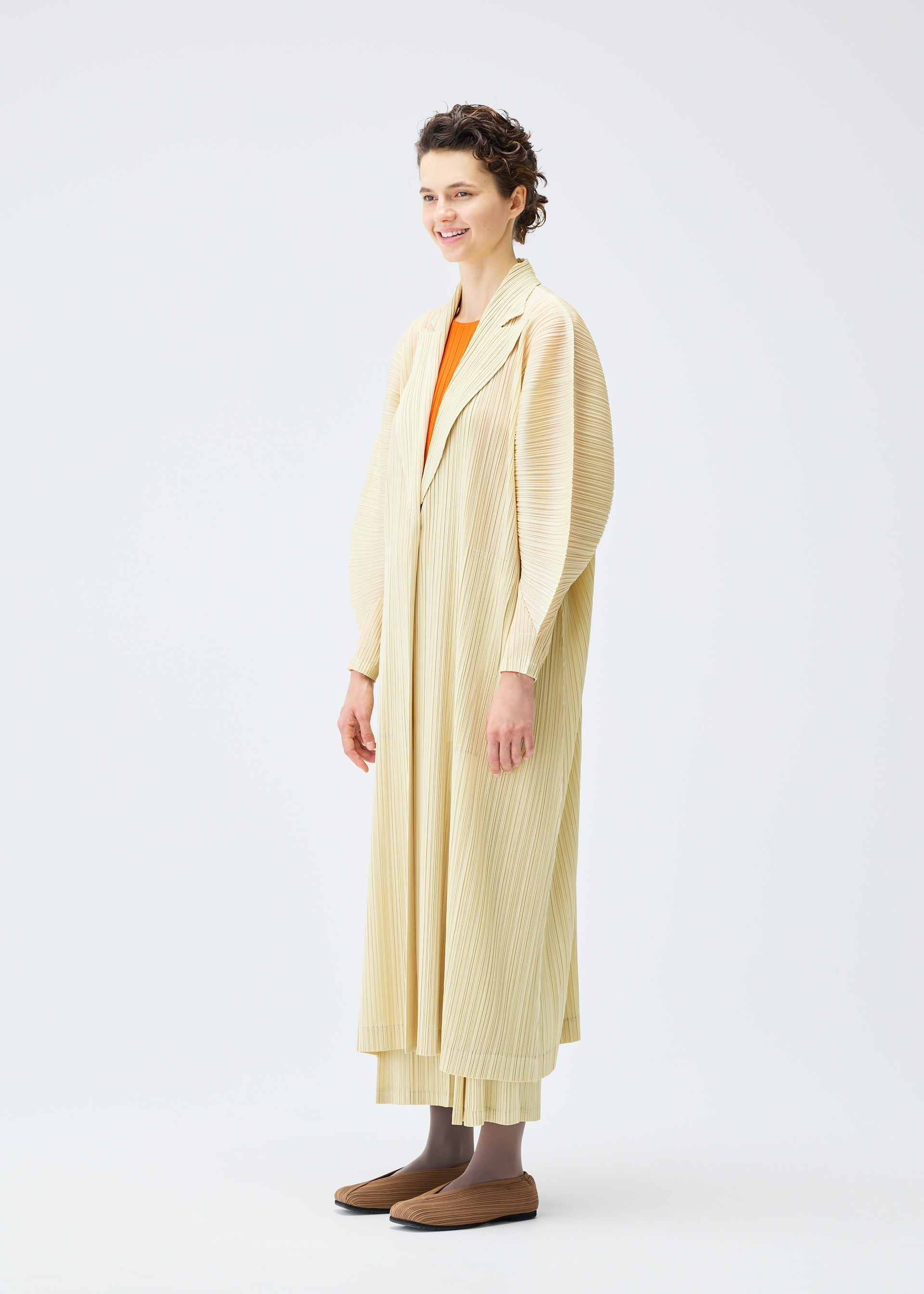 A model wears the PLEATS PLEASE ISSEY MIYAKE MONTHLY COLORS DECEMBER clothing.