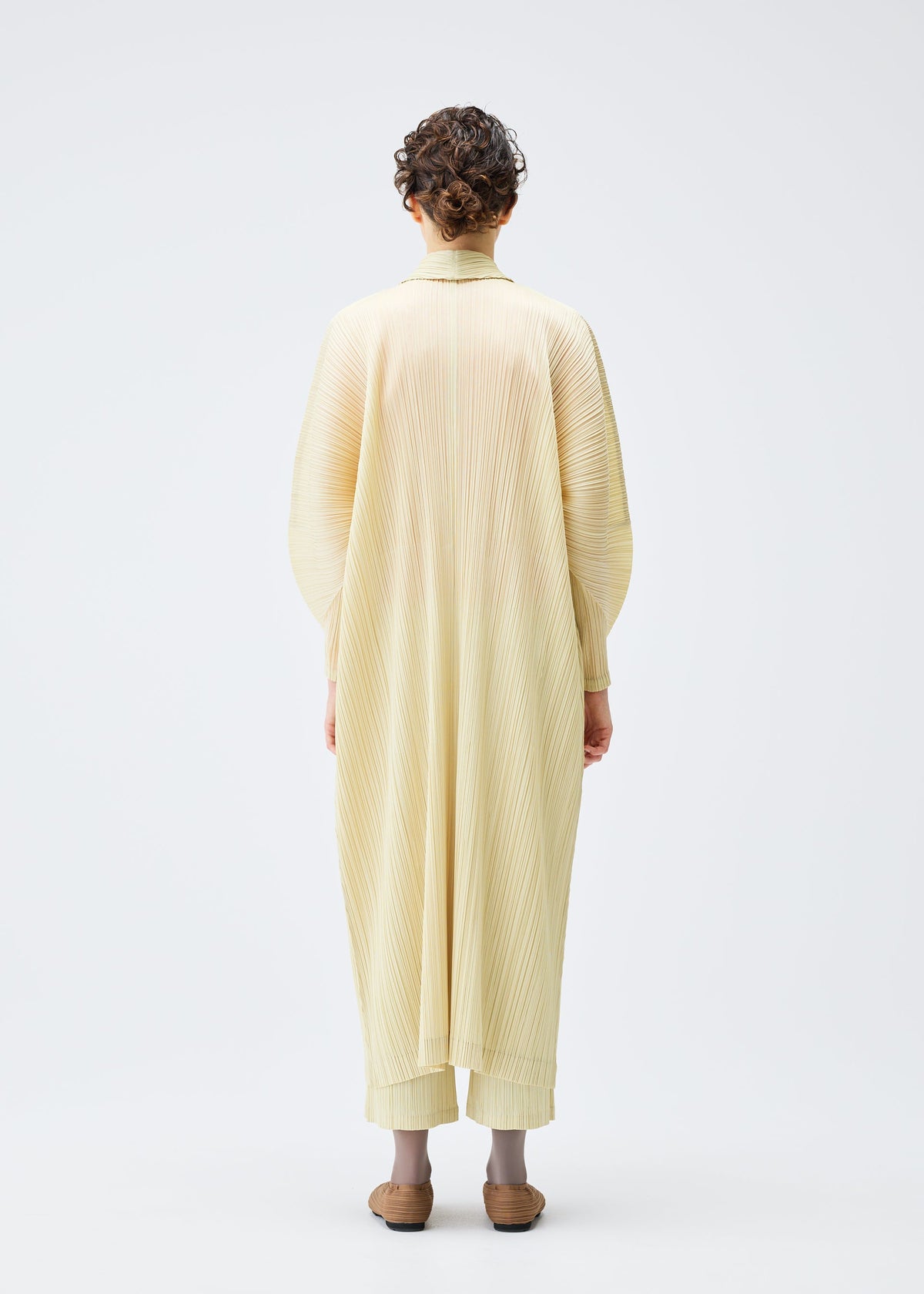 A model wears the PLEATS PLEASE ISSEY MIYAKE MONTHLY COLORS DECEMBER clothing.