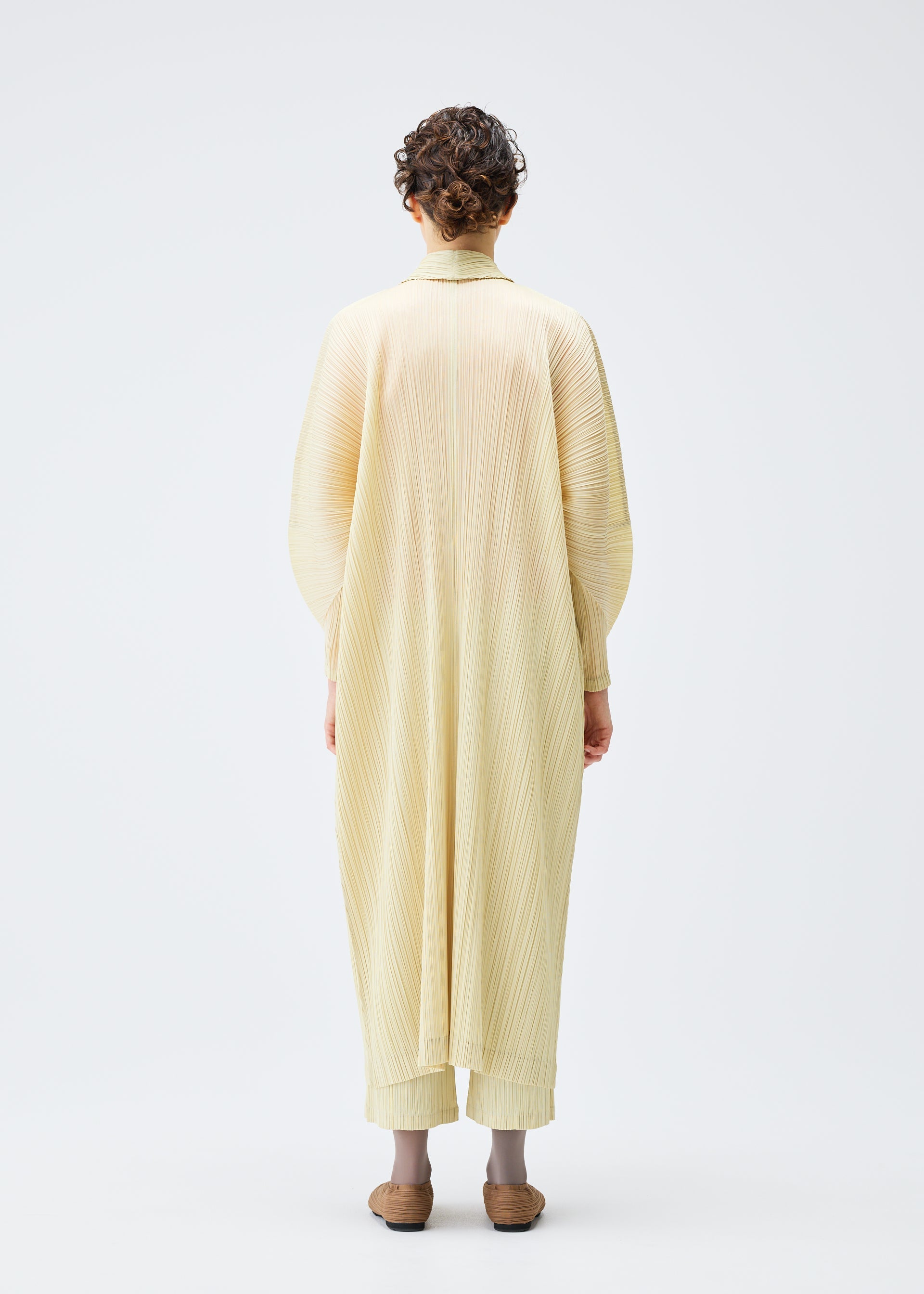 A model wears the PLEATS PLEASE ISSEY MIYAKE MONTHLY COLORS DECEMBER clothing.