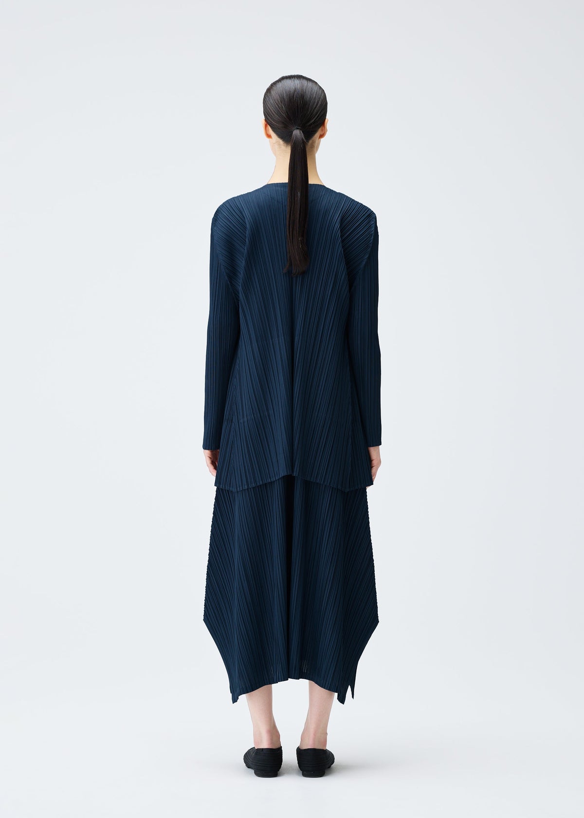 A model wears the PLEATS PLEASE ISSEY MIYAKE MELLOW PLEATS coat.