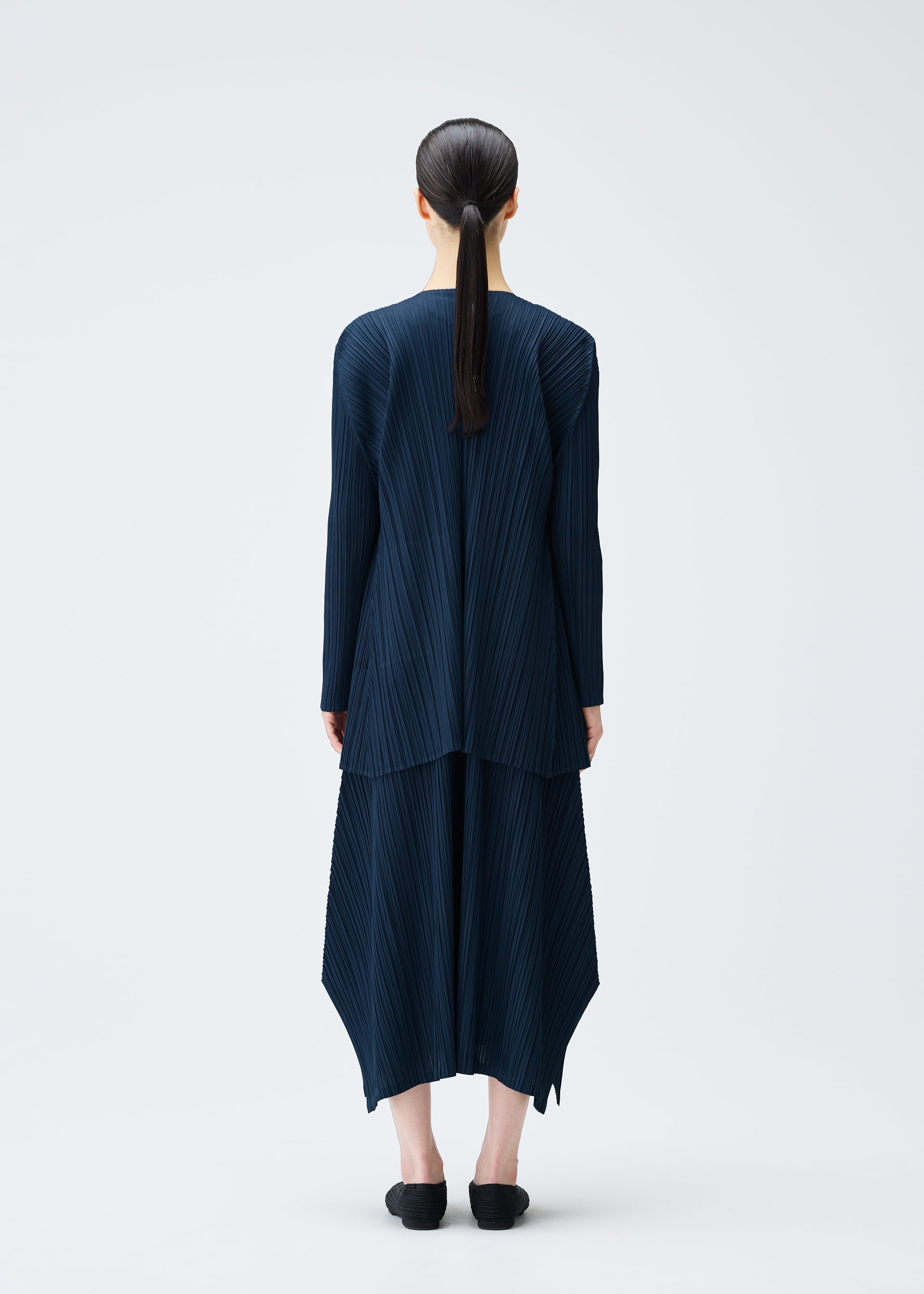 A model wears the PLEATS PLEASE ISSEY MIYAKE MELLOW PLEATS coat.