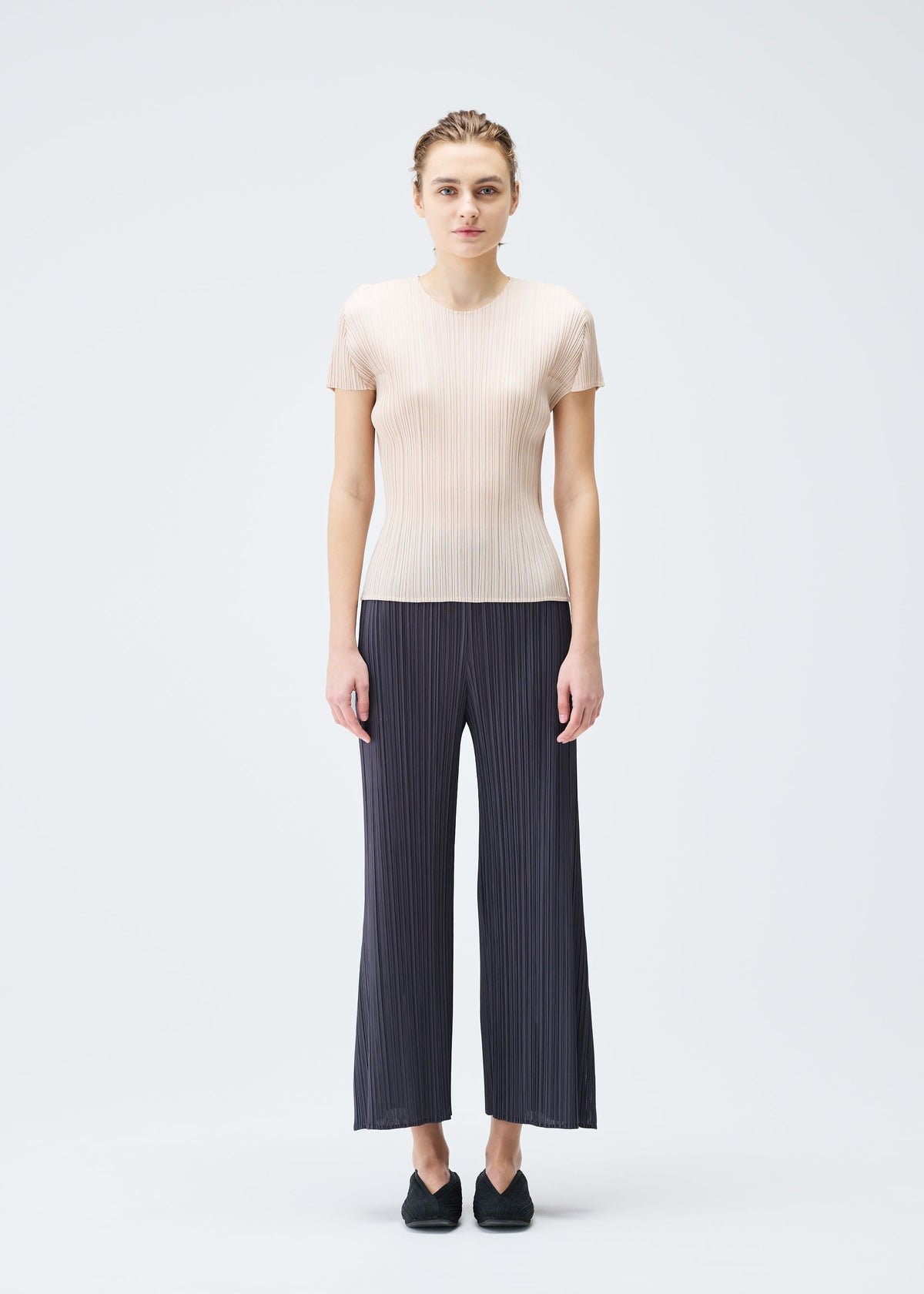 A model wears the PLEATS PLEASE ISSEY MIYAKE MONTHLY COLORS JULY trousers.