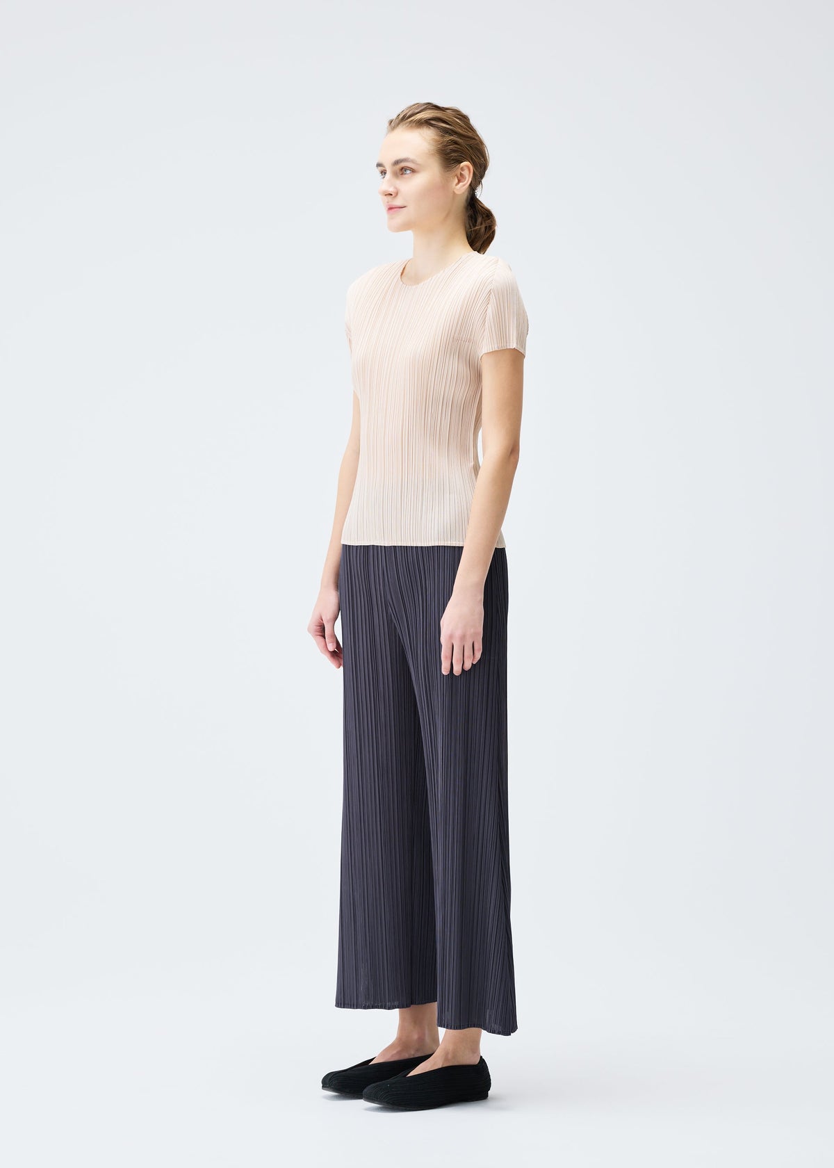 A model wears the PLEATS PLEASE ISSEY MIYAKE MONTHLY COLORS JULY trousers.