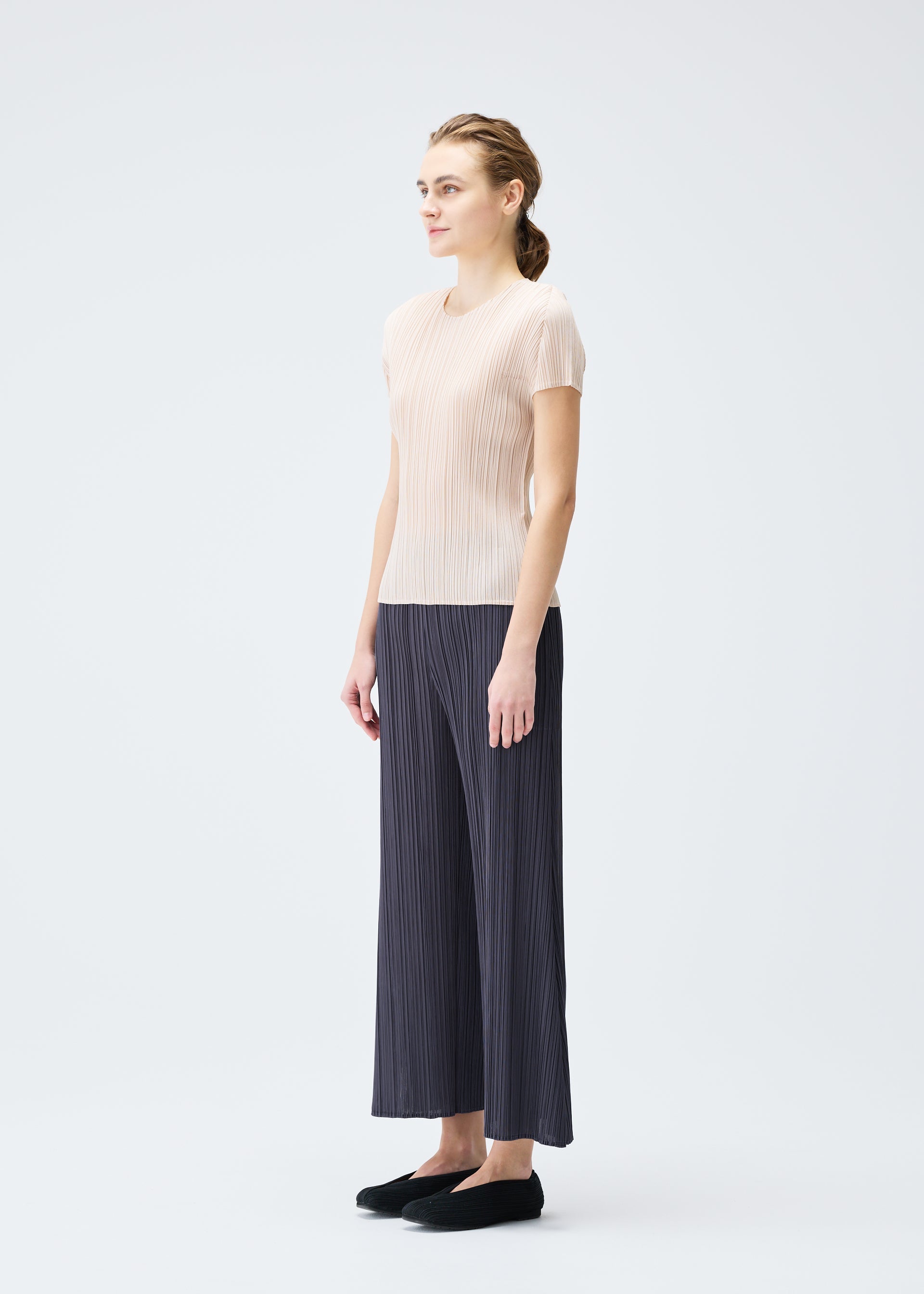 A model wears the PLEATS PLEASE ISSEY MIYAKE MONTHLY COLORS JULY trousers.