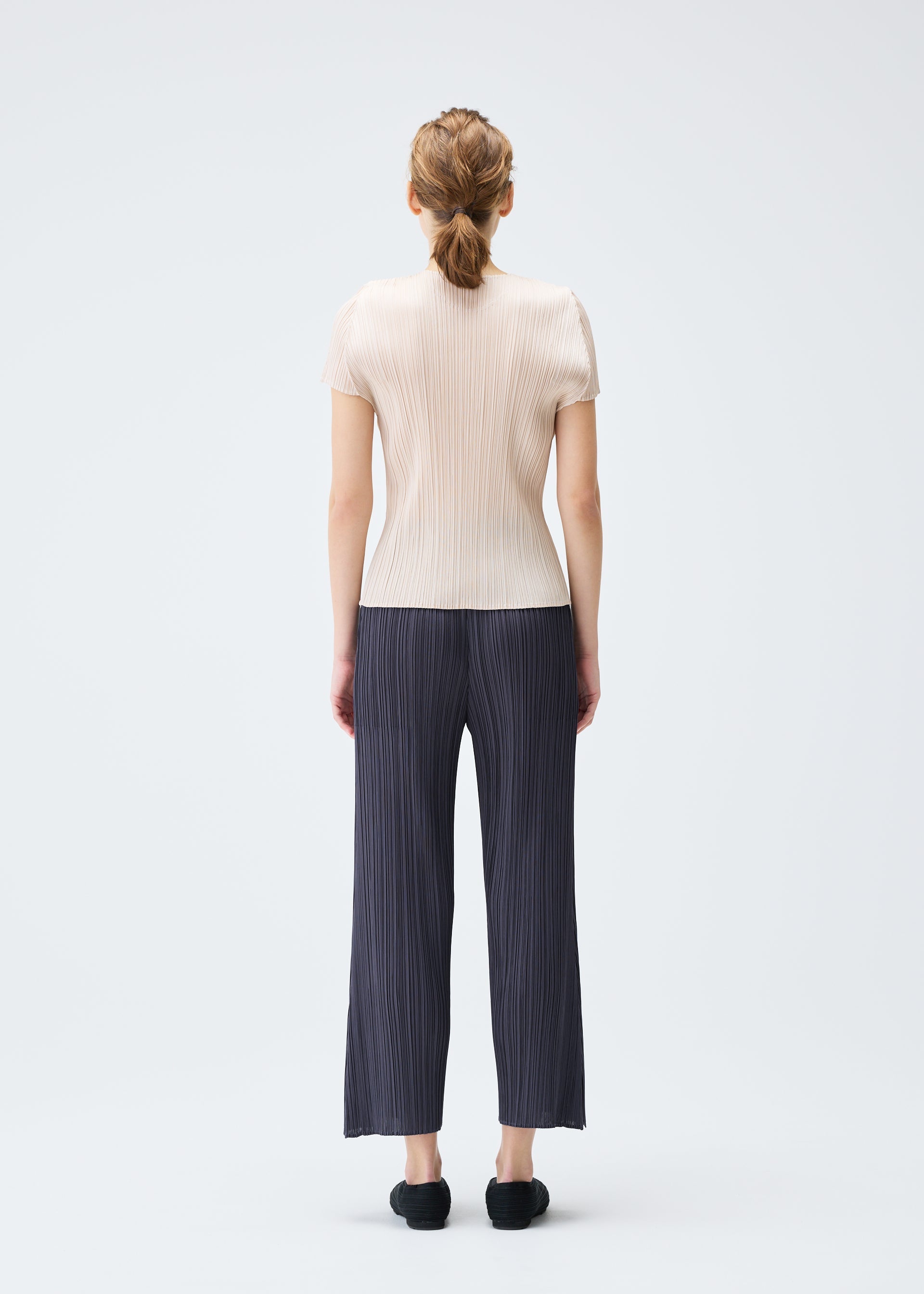 A model wears the PLEATS PLEASE ISSEY MIYAKE MONTHLY COLORS JULY trousers.