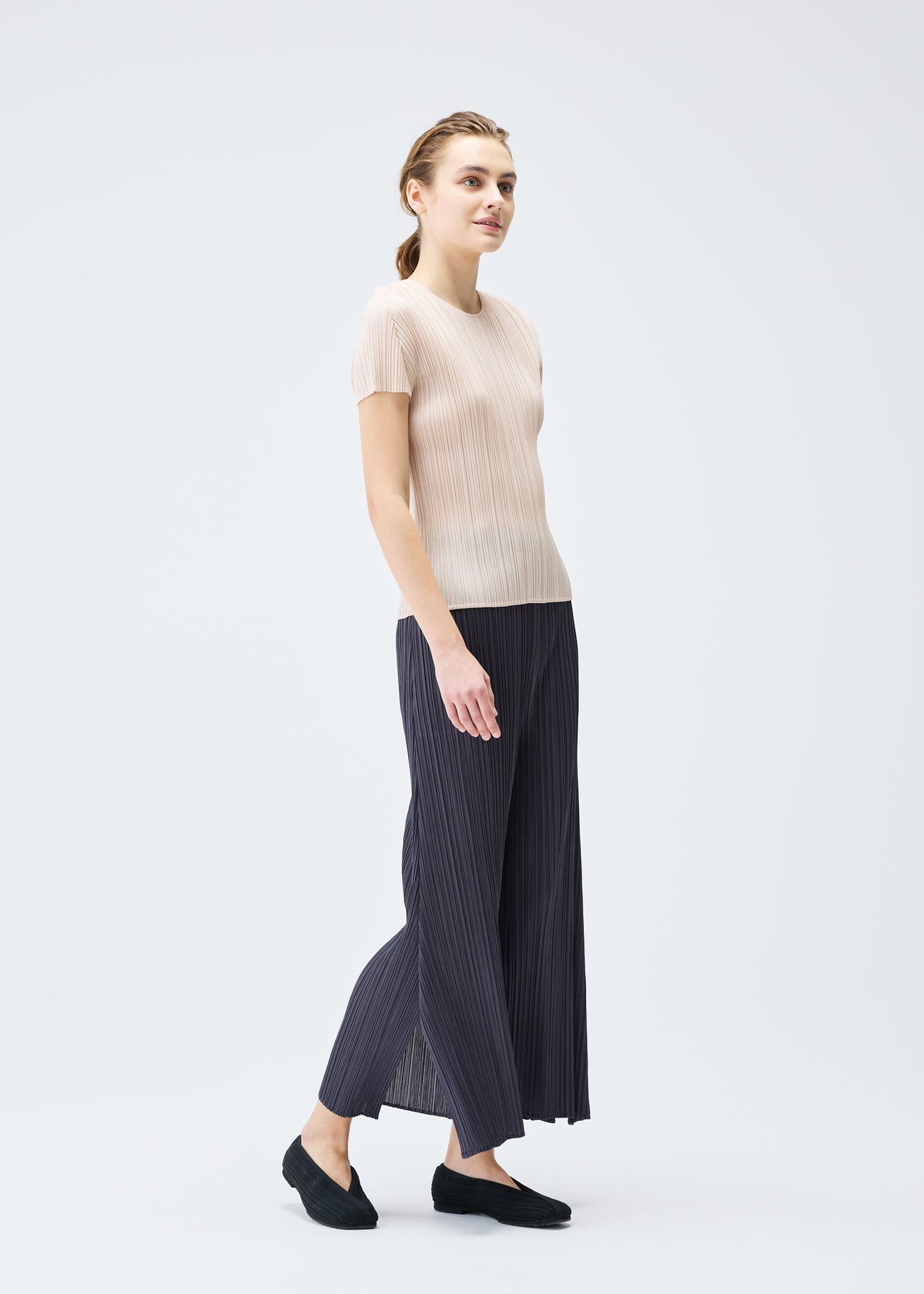 A model wears the PLEATS PLEASE ISSEY MIYAKE MONTHLY COLORS JULY trousers.