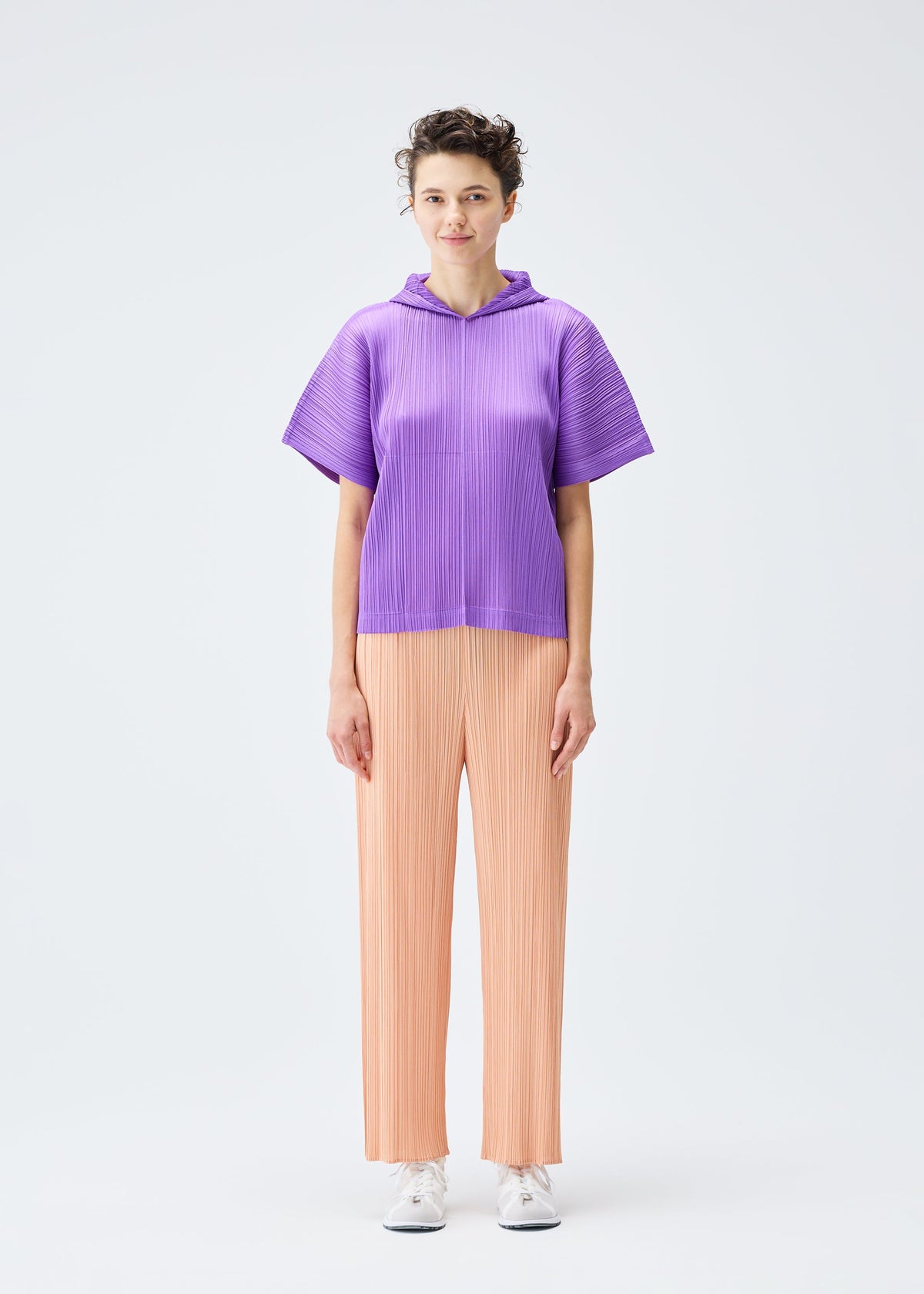 A model wears the PLEATS PLEASE ISSEY MIYAKE MONTHLY COLORS AUGUST trousers.