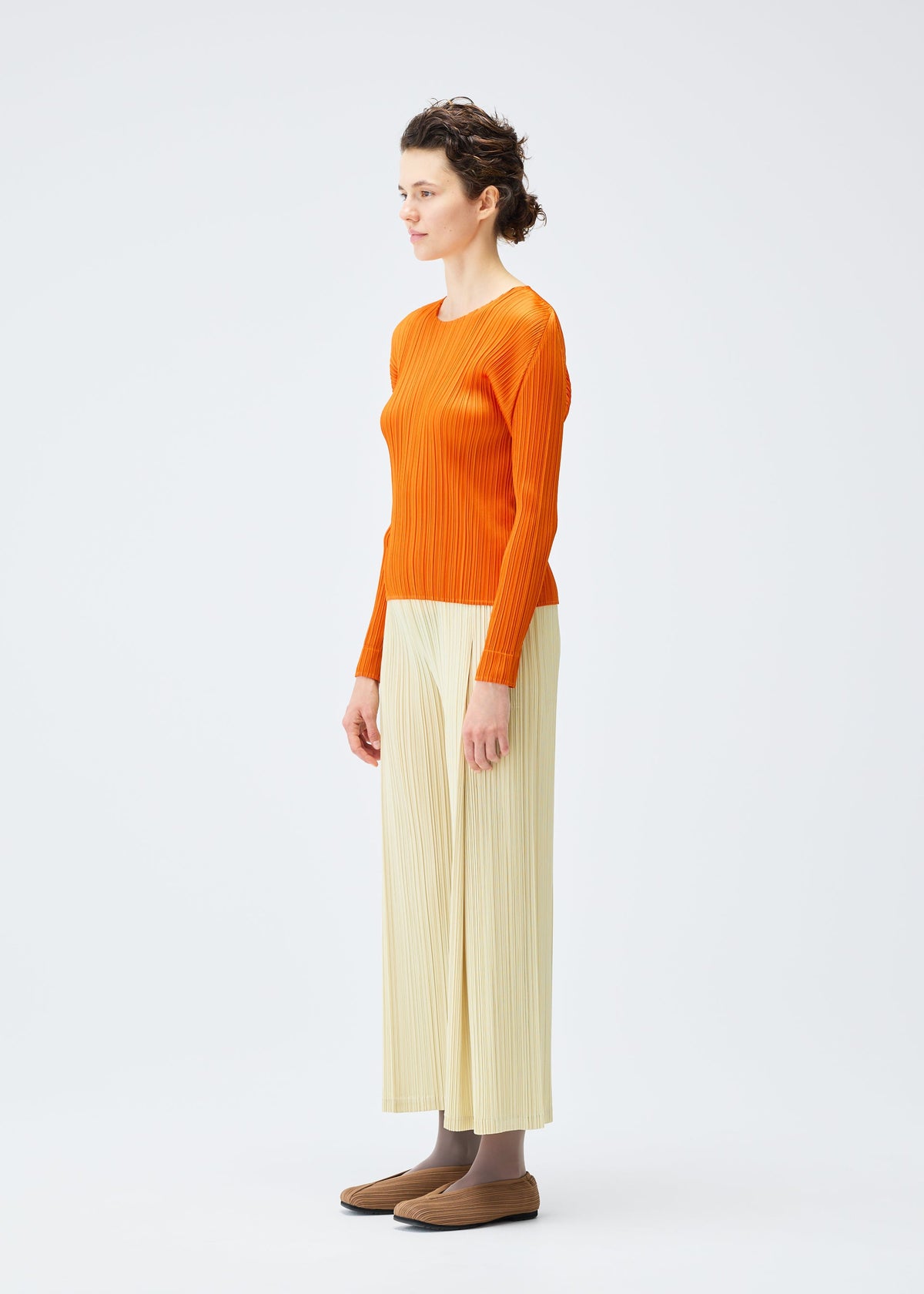 A model wears the PLEATS PLEASE ISSEY MIYAKE MONTHLY COLORS DECEMBER clothing.