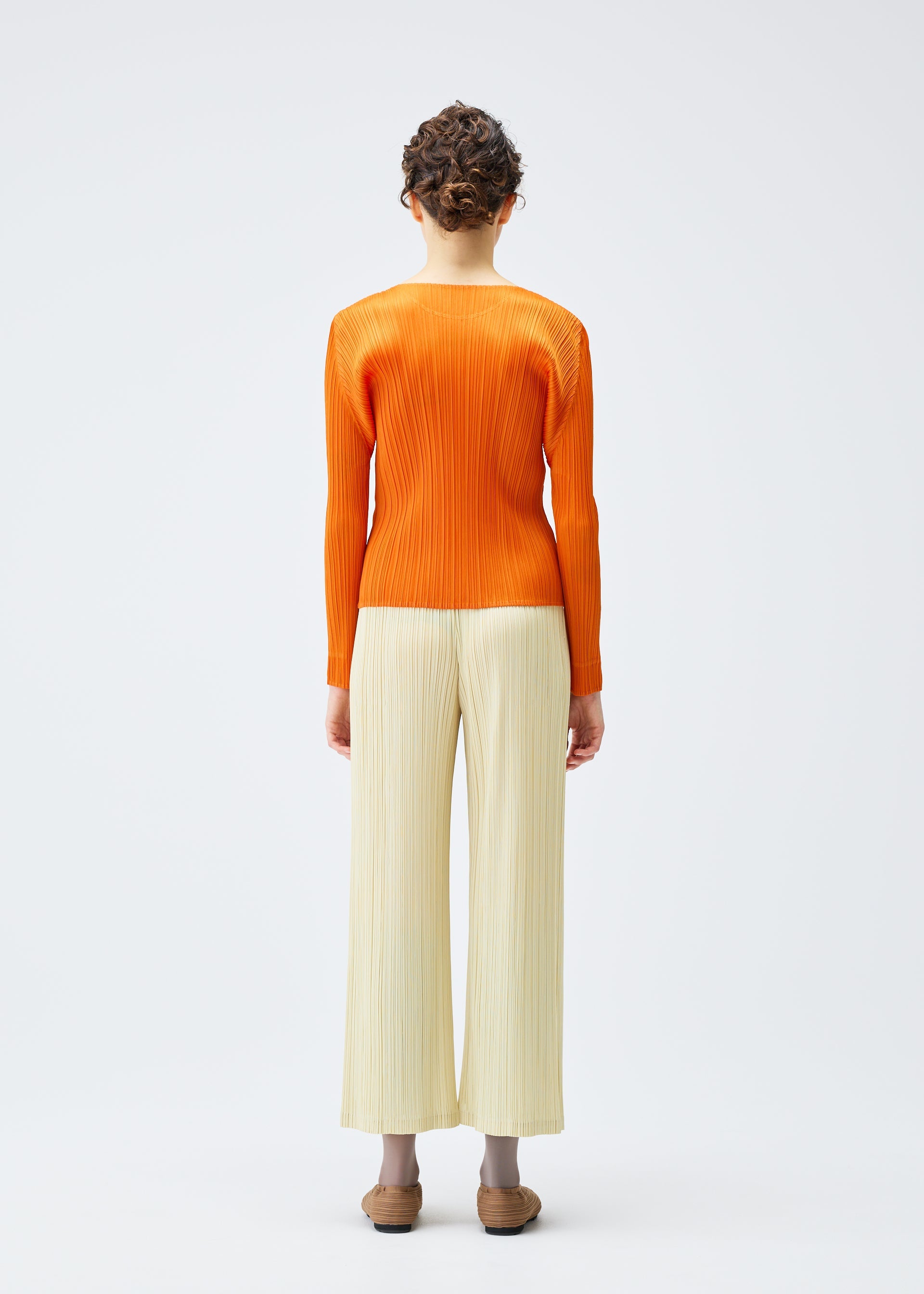A model wears the PLEATS PLEASE ISSEY MIYAKE MONTHLY COLORS DECEMBER clothing.