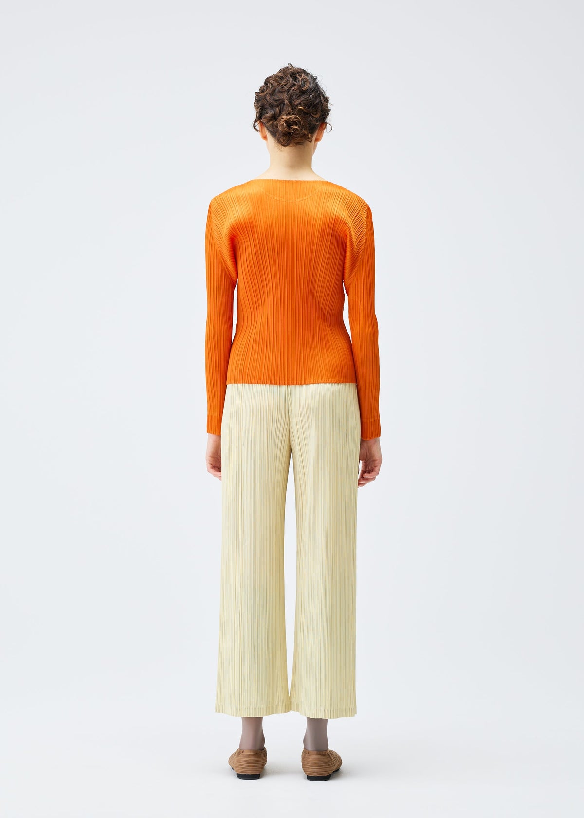 A model wears the PLEATS PLEASE ISSEY MIYAKE MONTHLY COLORS DECEMBER clothing.